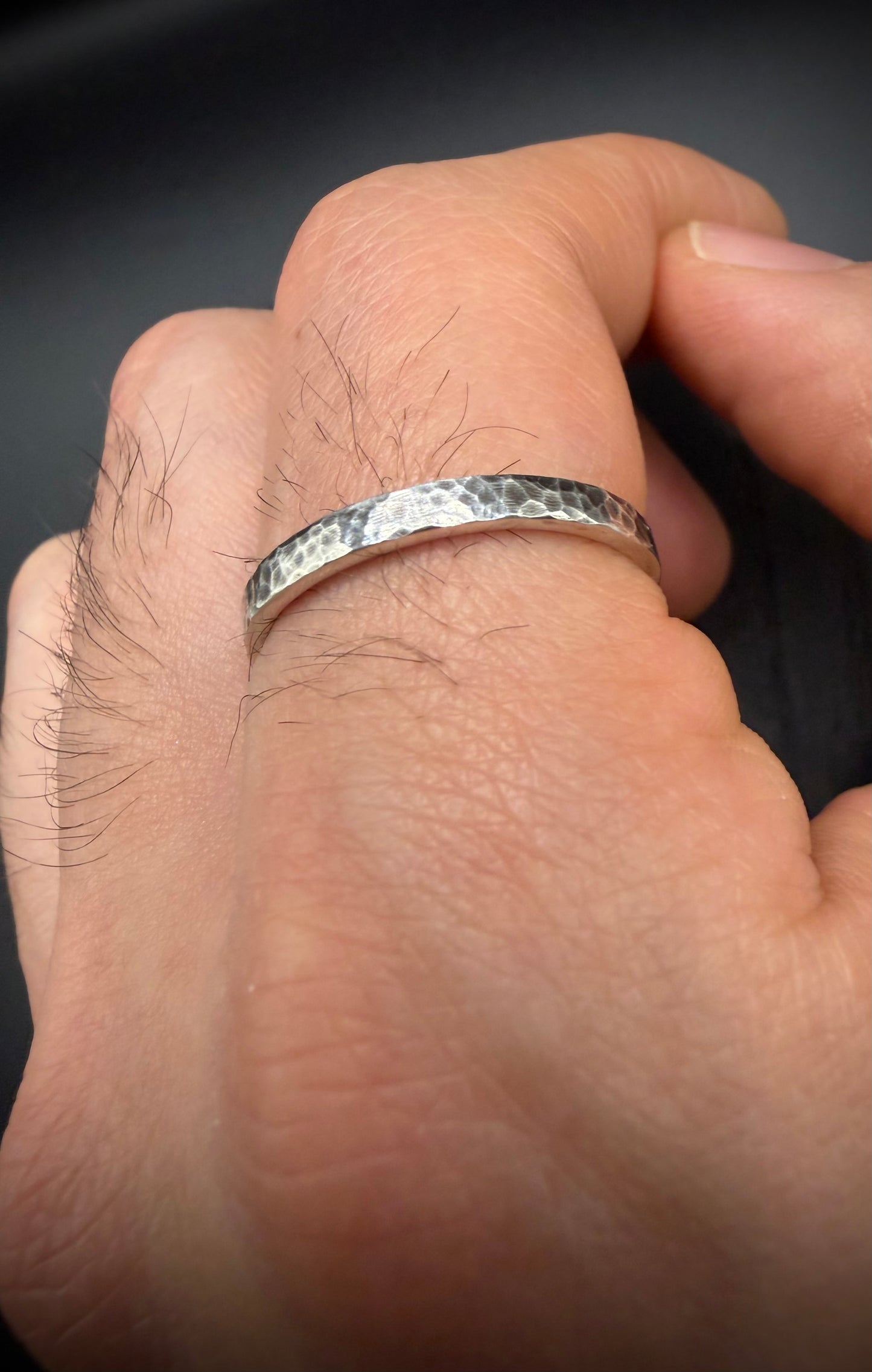 Close-up of a textured sterling silver ring, known as the Blackwood Band, being worn to show scale and fit. The hammered finish highlights the unique artisan quality of the silver jewelry.