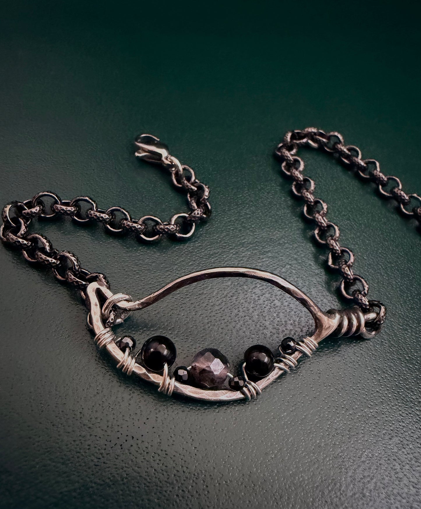 Silver textured Leaf bracelet on a dark green background.