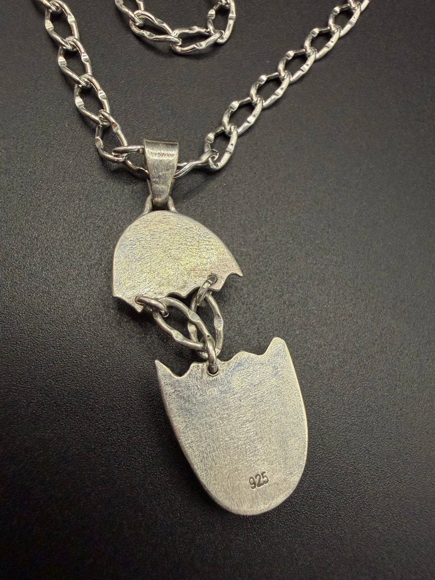 Silver necklace with a broken heart pendant on a dark background