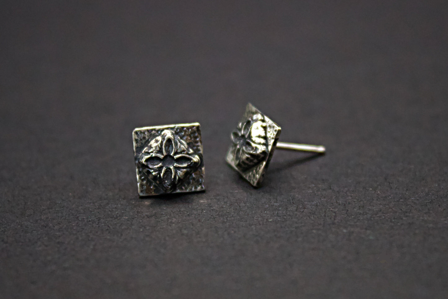 Pair of silver square earrings on a dark background