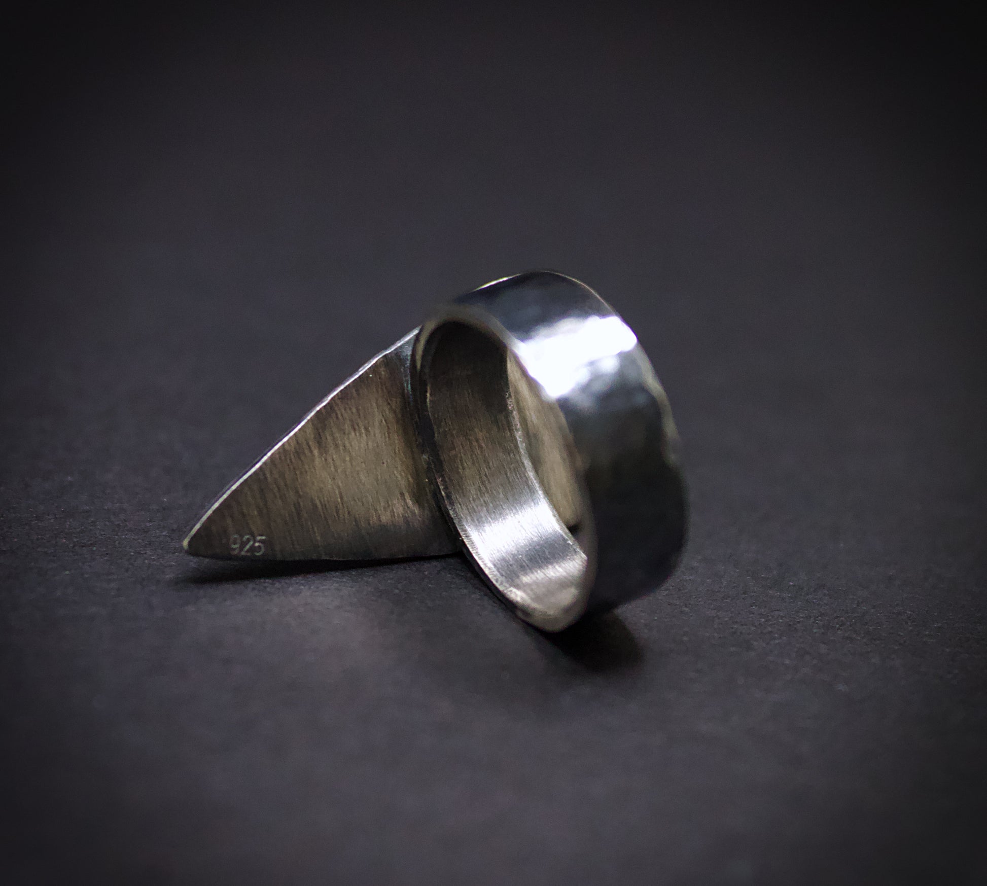 Silver ring with a unique design on a dark background