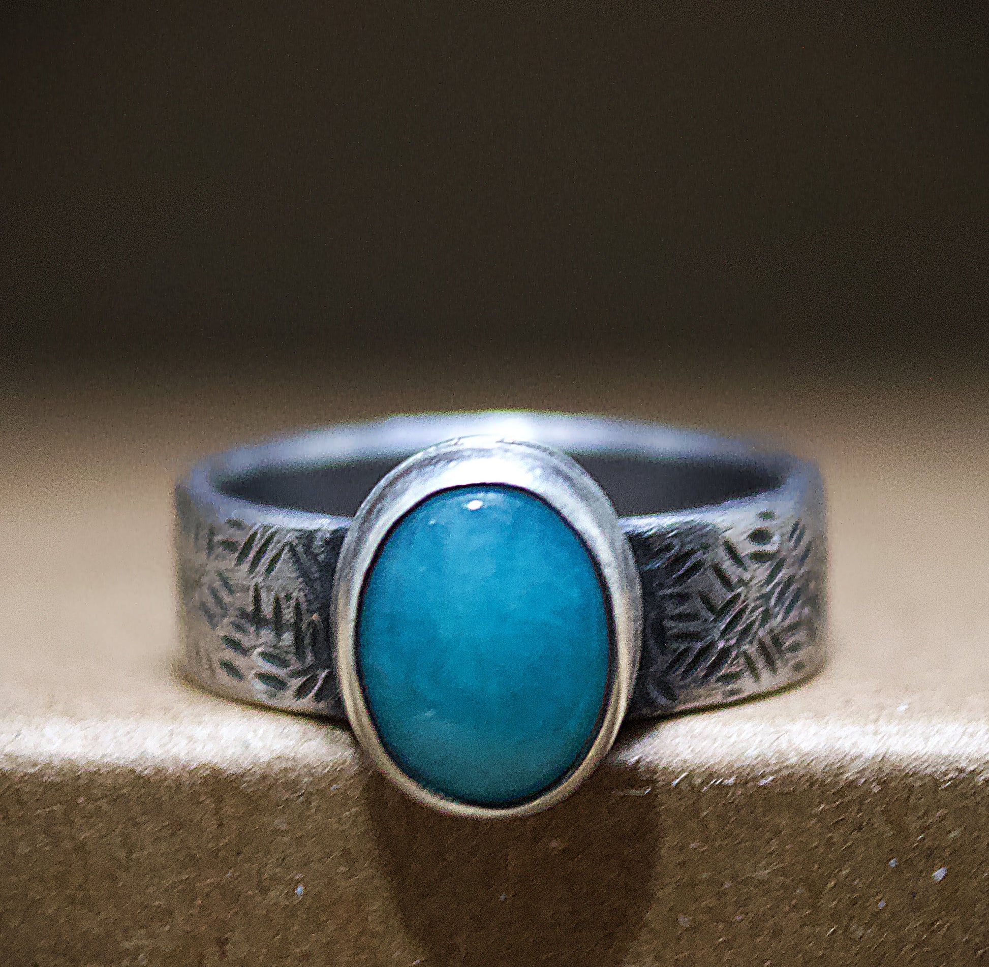 Silver ring with a turquoise stone on a textured surface