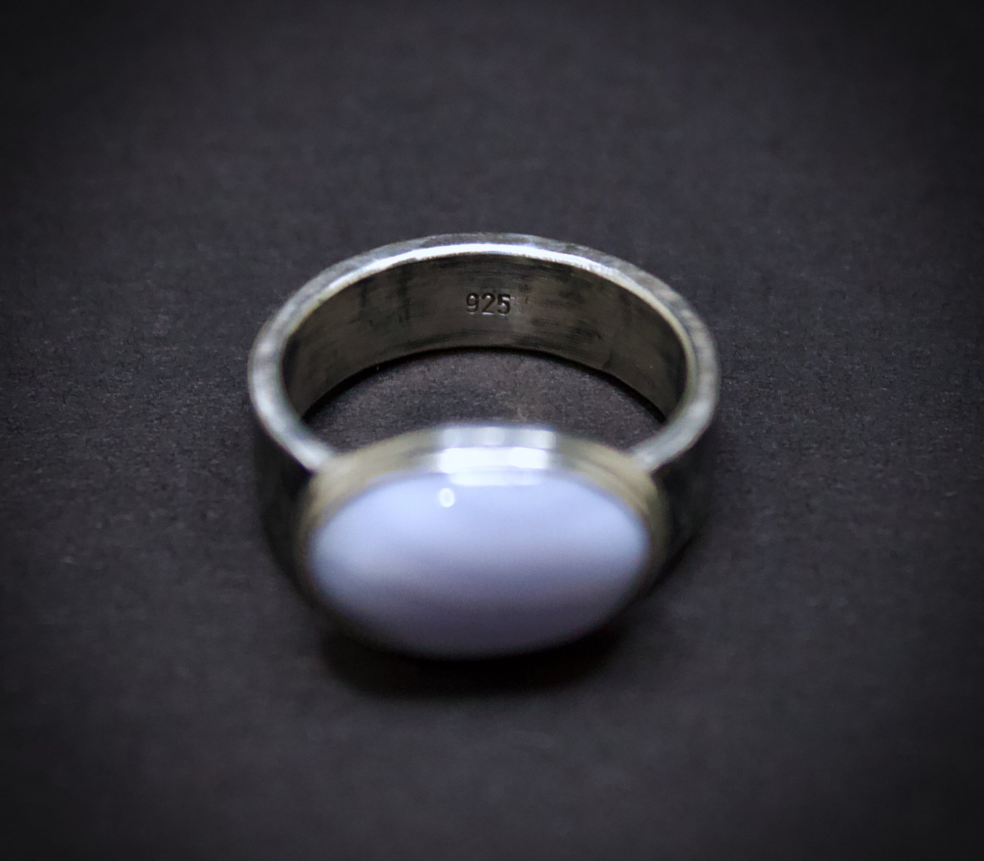 Silver ring with a purple stone on a dark background