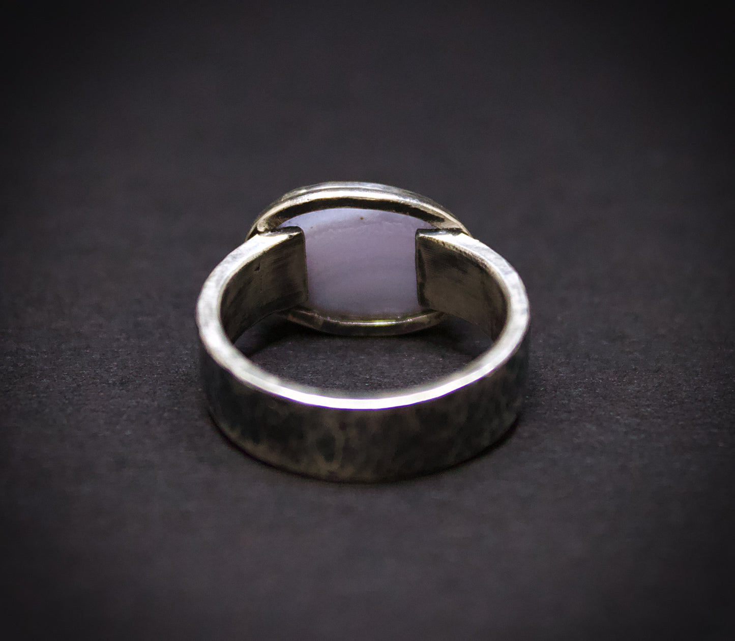 Silver ring with a unique design on a dark background