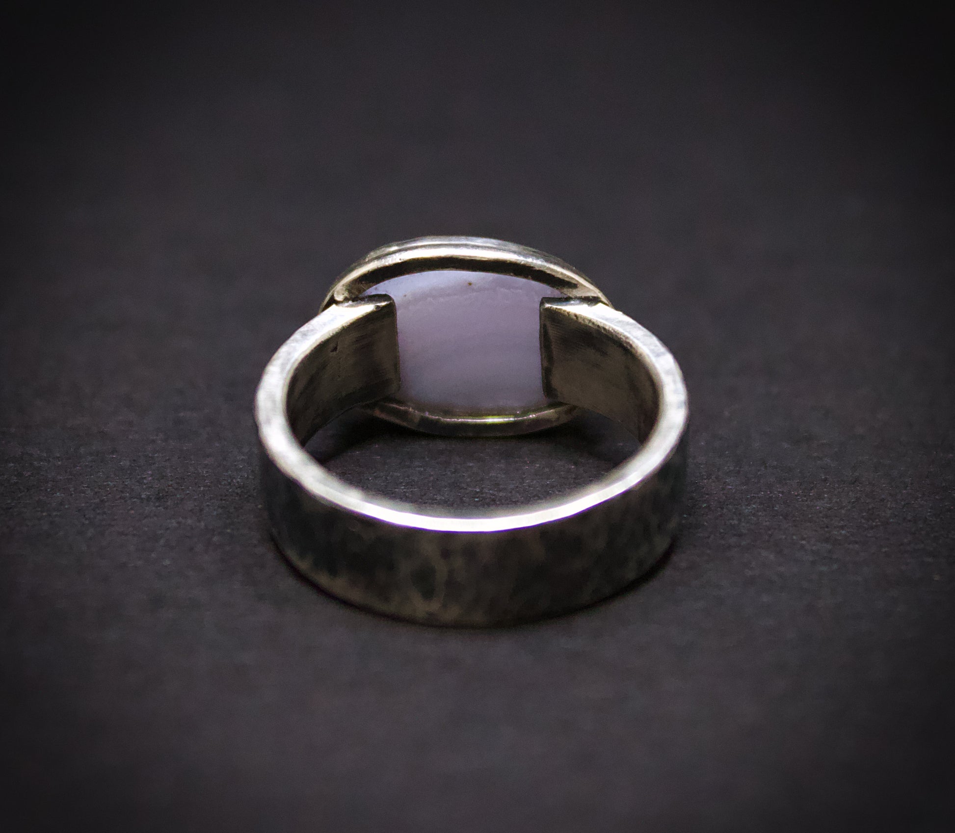 Silver ring with a unique design on a dark background