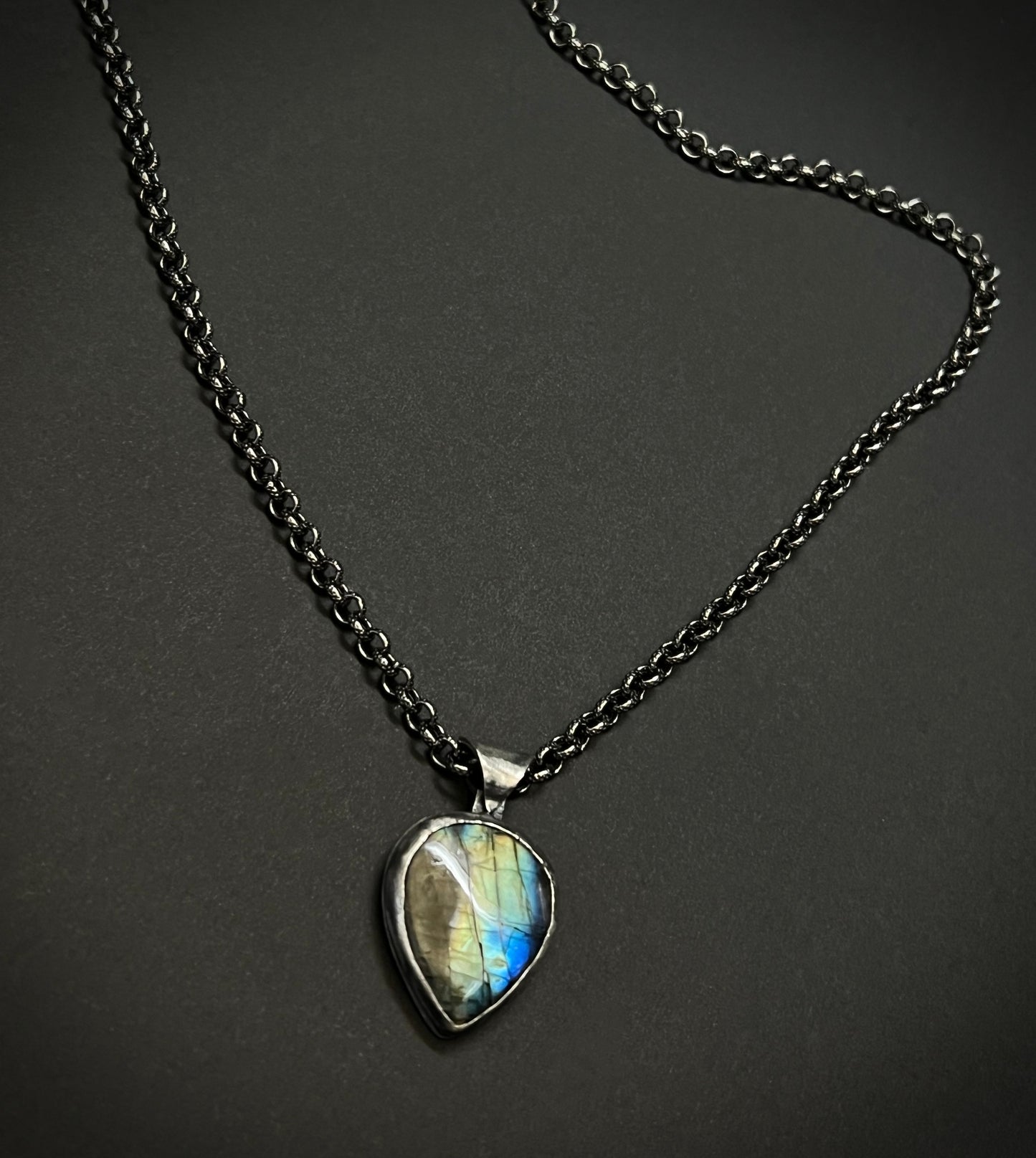Necklace with a teardrop-shaped labradorite pendant on a dark background