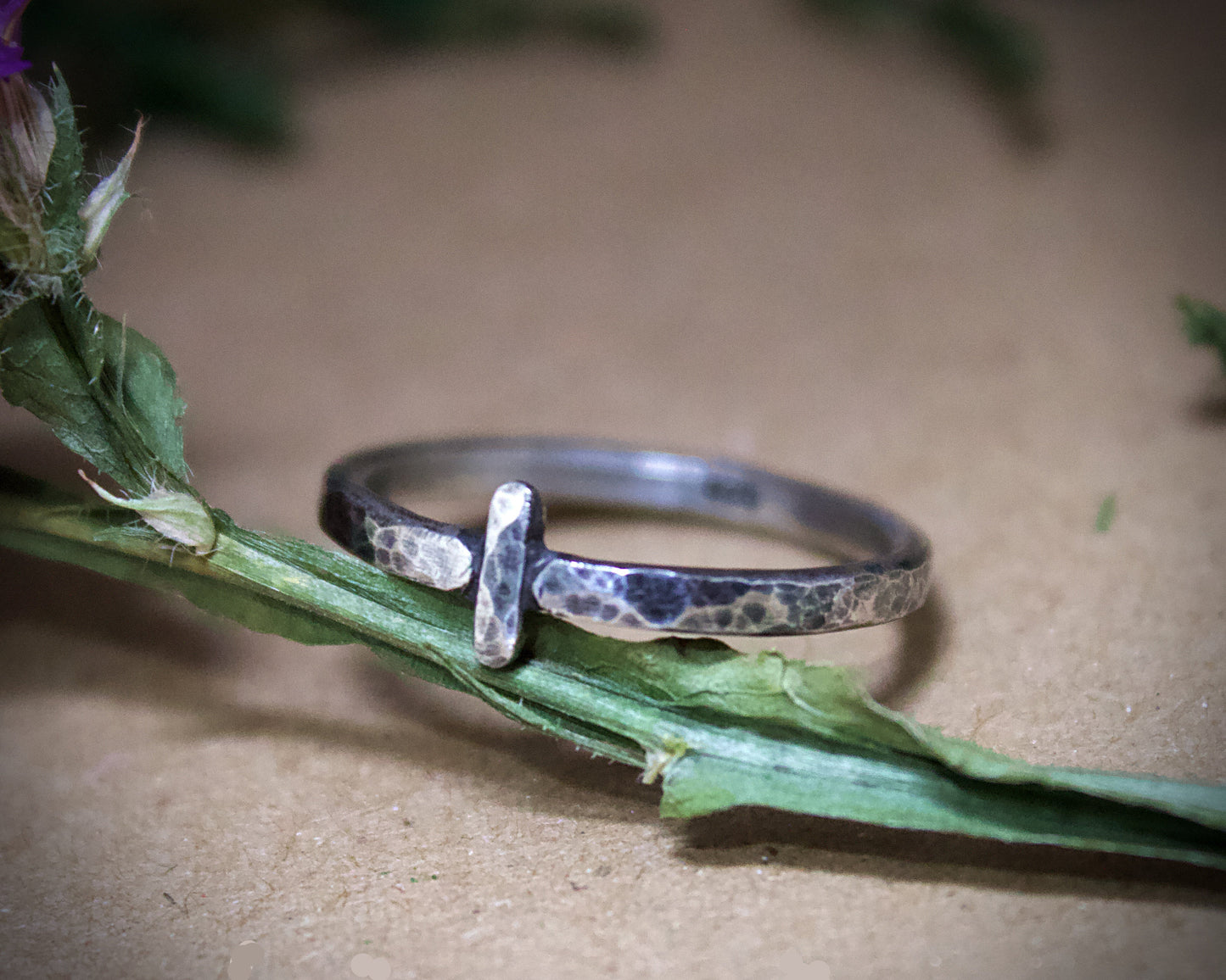 Silver ring with a textured design on a green leaf