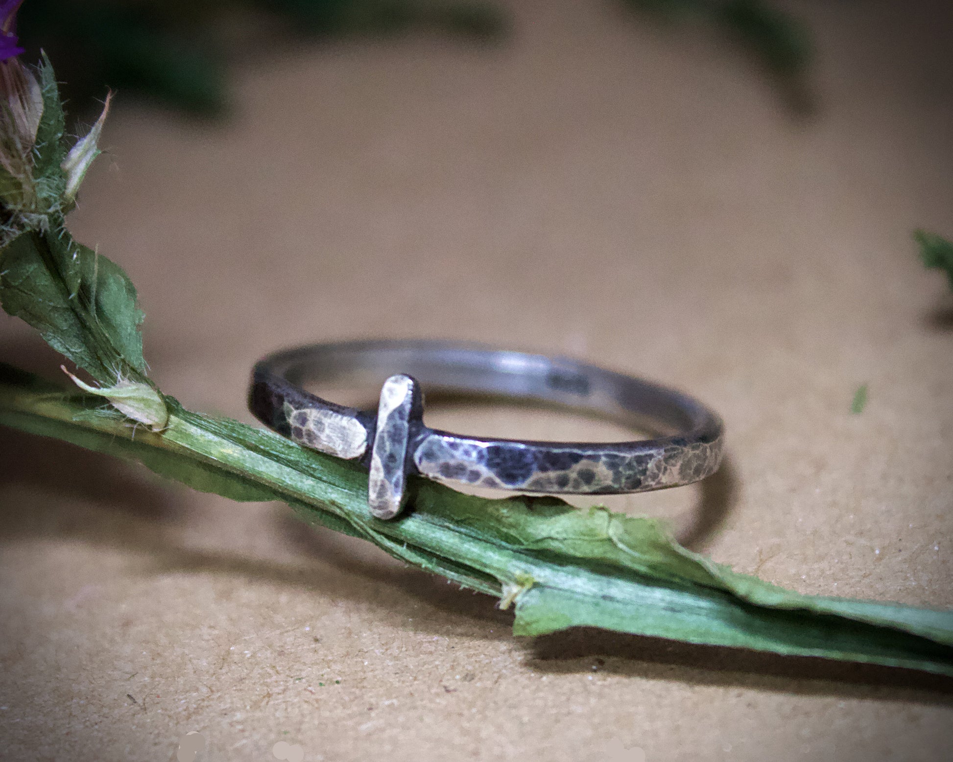 Silver ring with a textured design on a green leaf