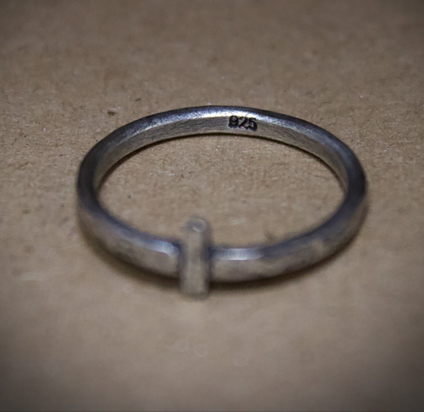 Silver ring with '925' stamp on a beige surface