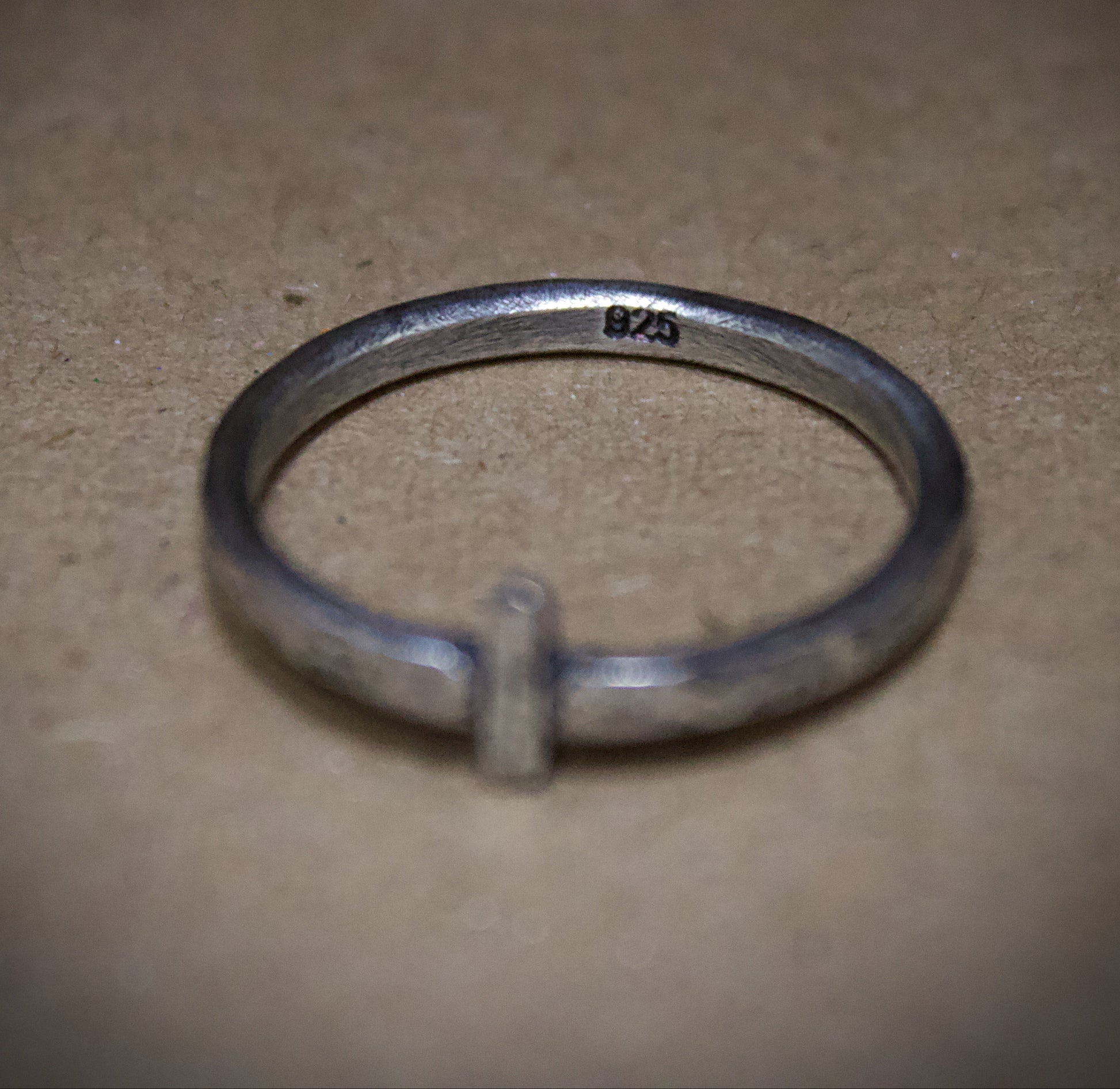 Silver ring with '925' stamp on a beige surface