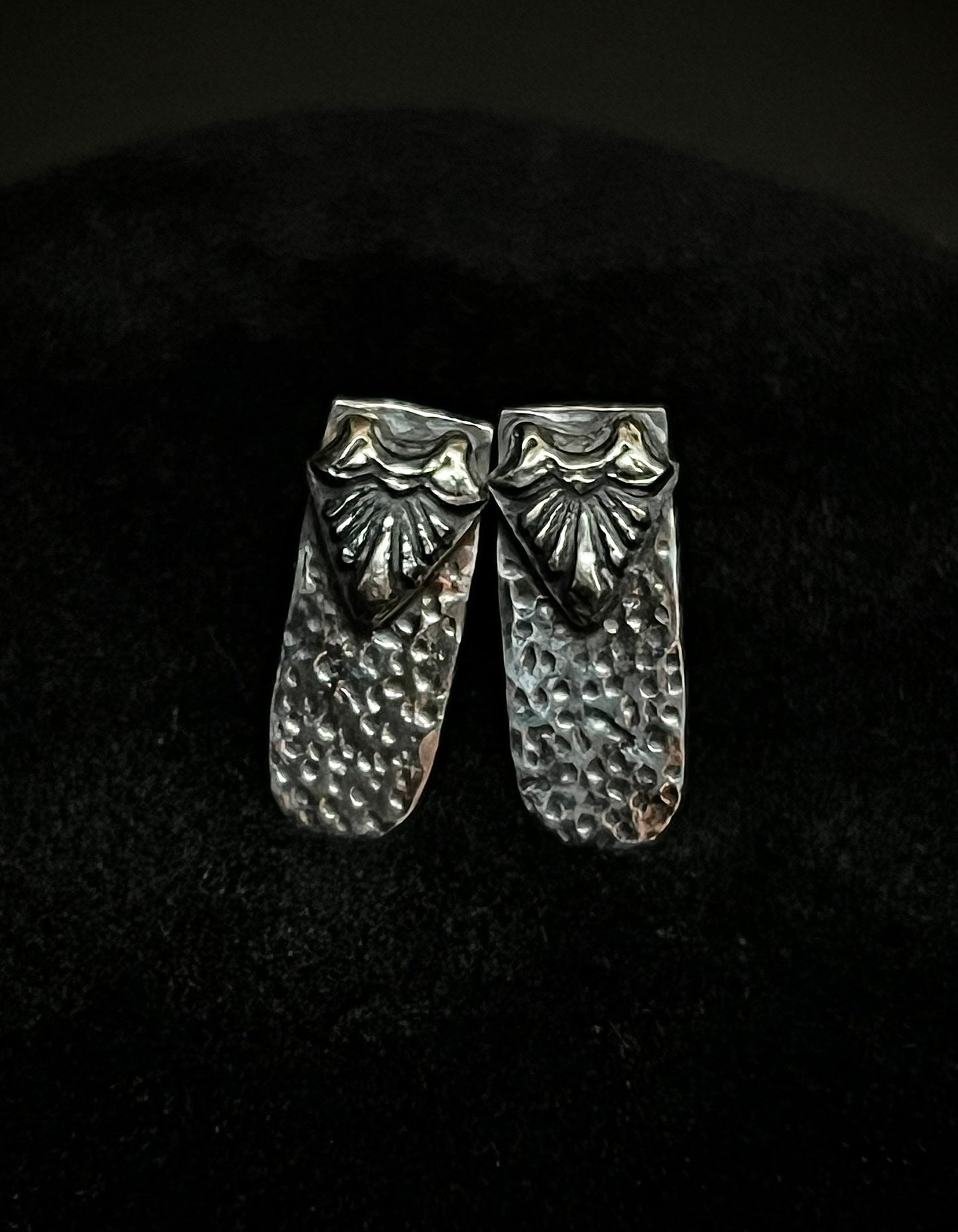 Close-up of Ashborn Root sterling silver studs with a vintage-inspired radiating design and hammered texture, set against a moody dark background for a Dark Academia aesthetic.