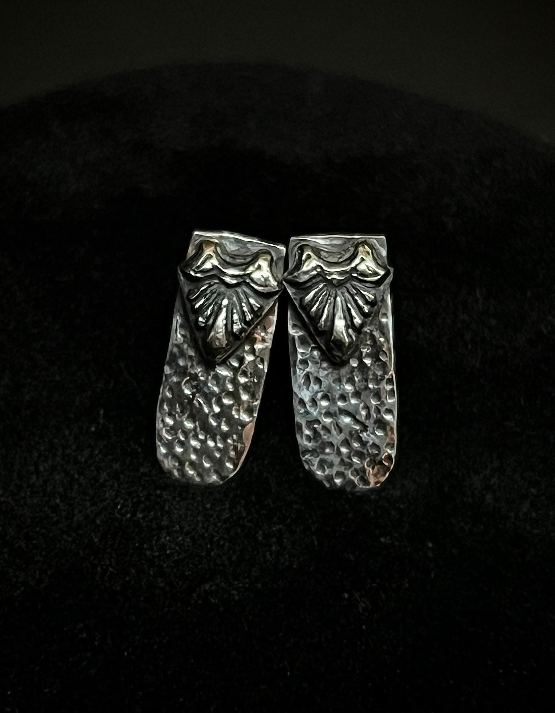 Close-up of Ashborn Root sterling silver studs with a vintage-inspired radiating design and hammered texture, set against a moody dark background for a Dark Academia aesthetic.