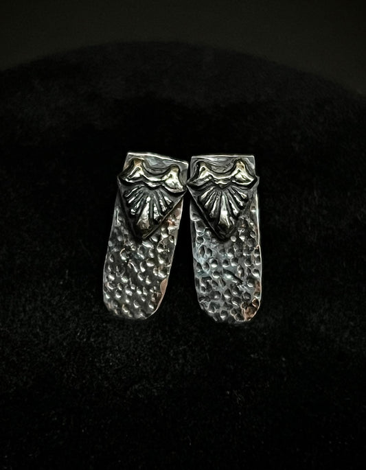Close-up of Ashborn Root sterling silver studs with a vintage-inspired radiating design and hammered texture, set against a moody dark background for a Dark Academia aesthetic.