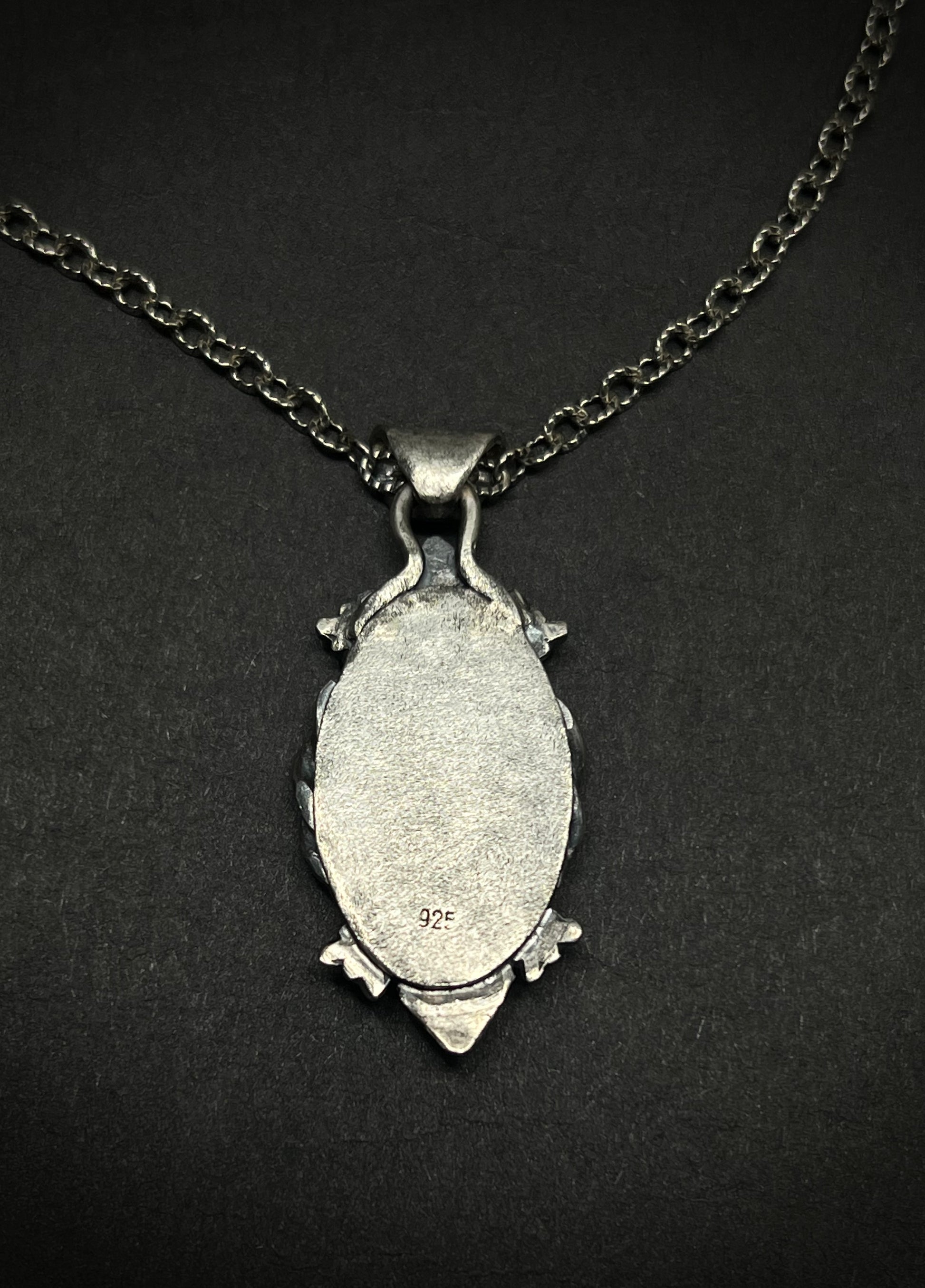Silver pendant necklace on a black background