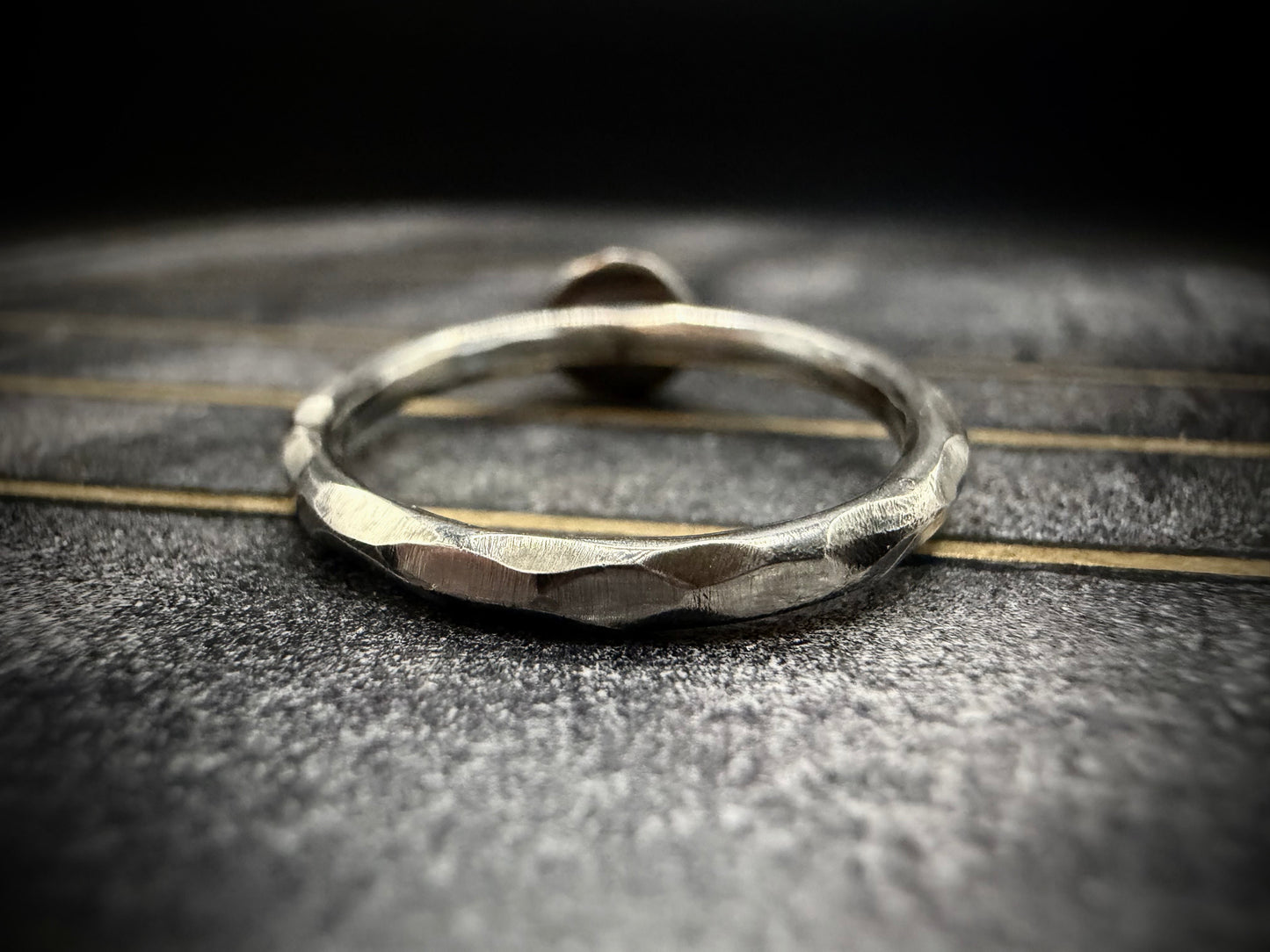 Silver ring with textured surface on a dark textured surface