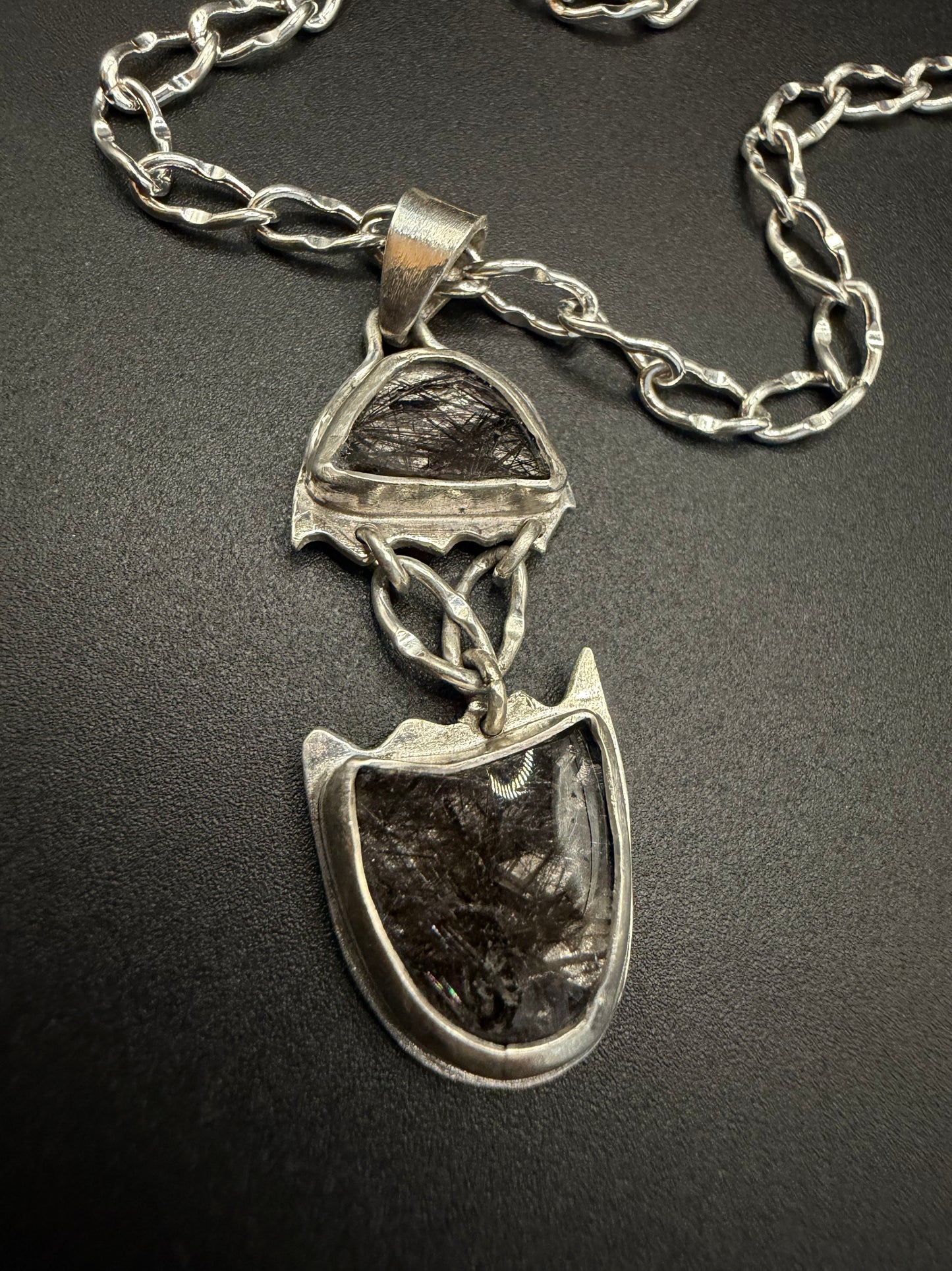 Silver necklace with a unique pendant on a dark background