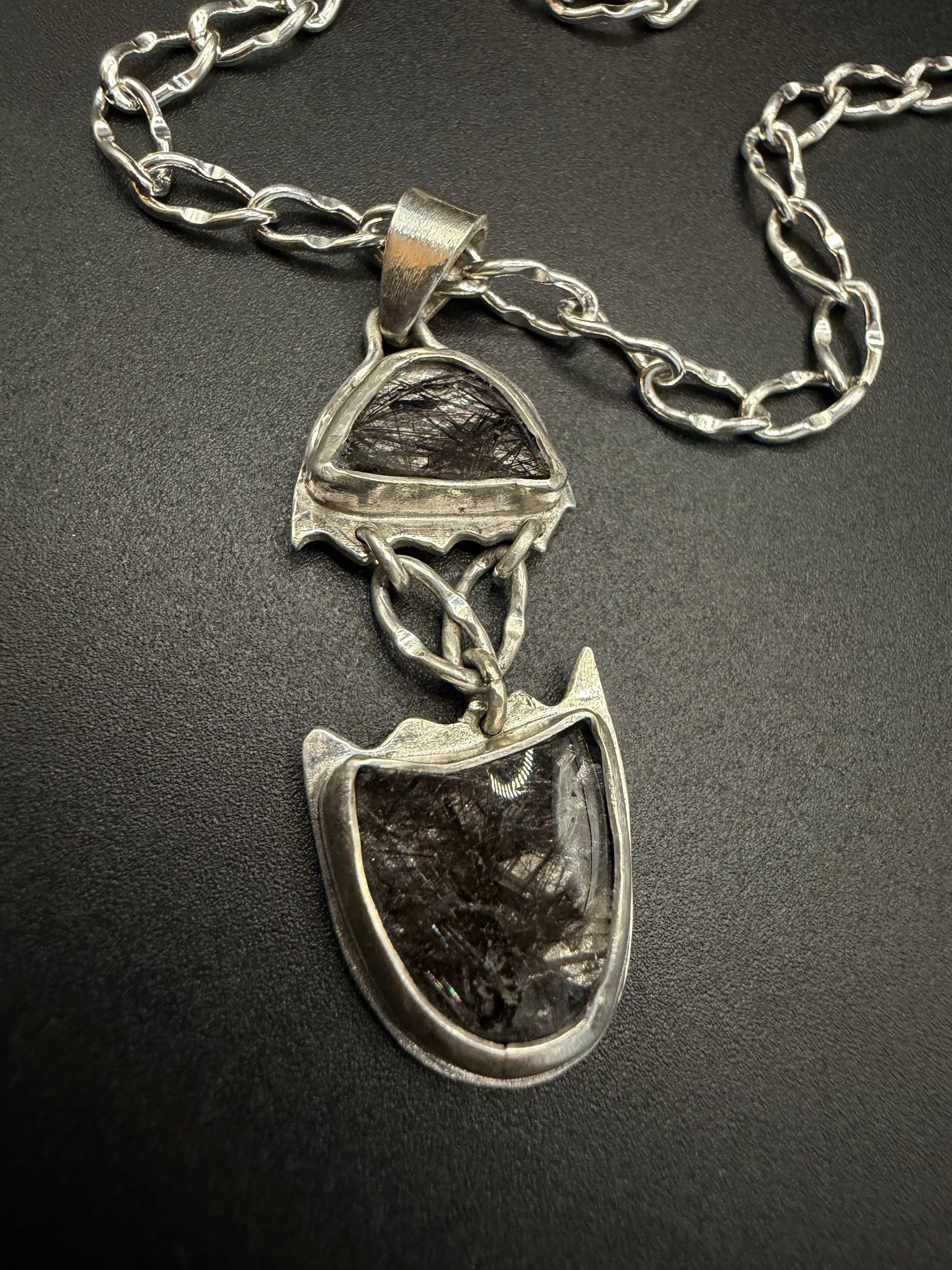 Silver necklace with a unique pendant on a dark background