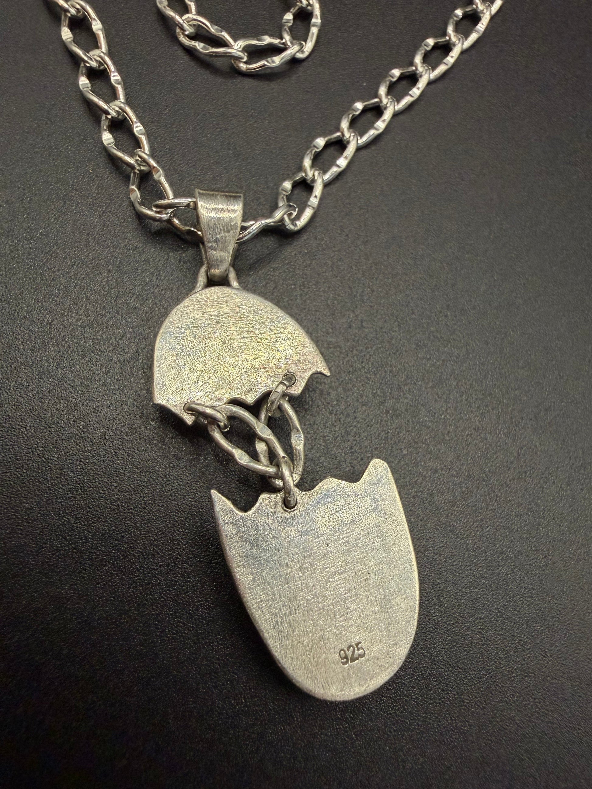 Silver necklace with a broken heart pendant on a dark background