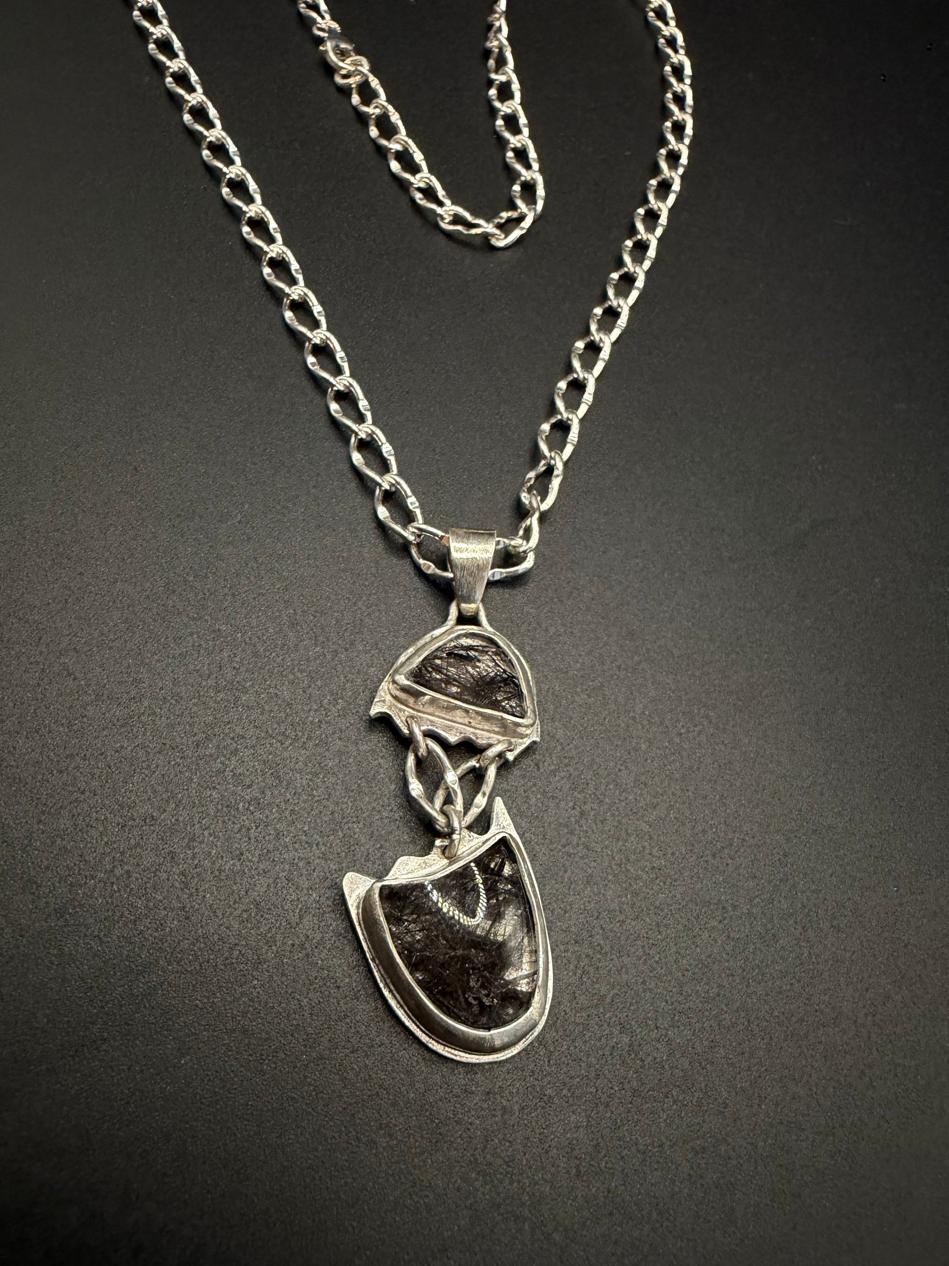 Silver necklace with a heart-shaped pendant on a dark background