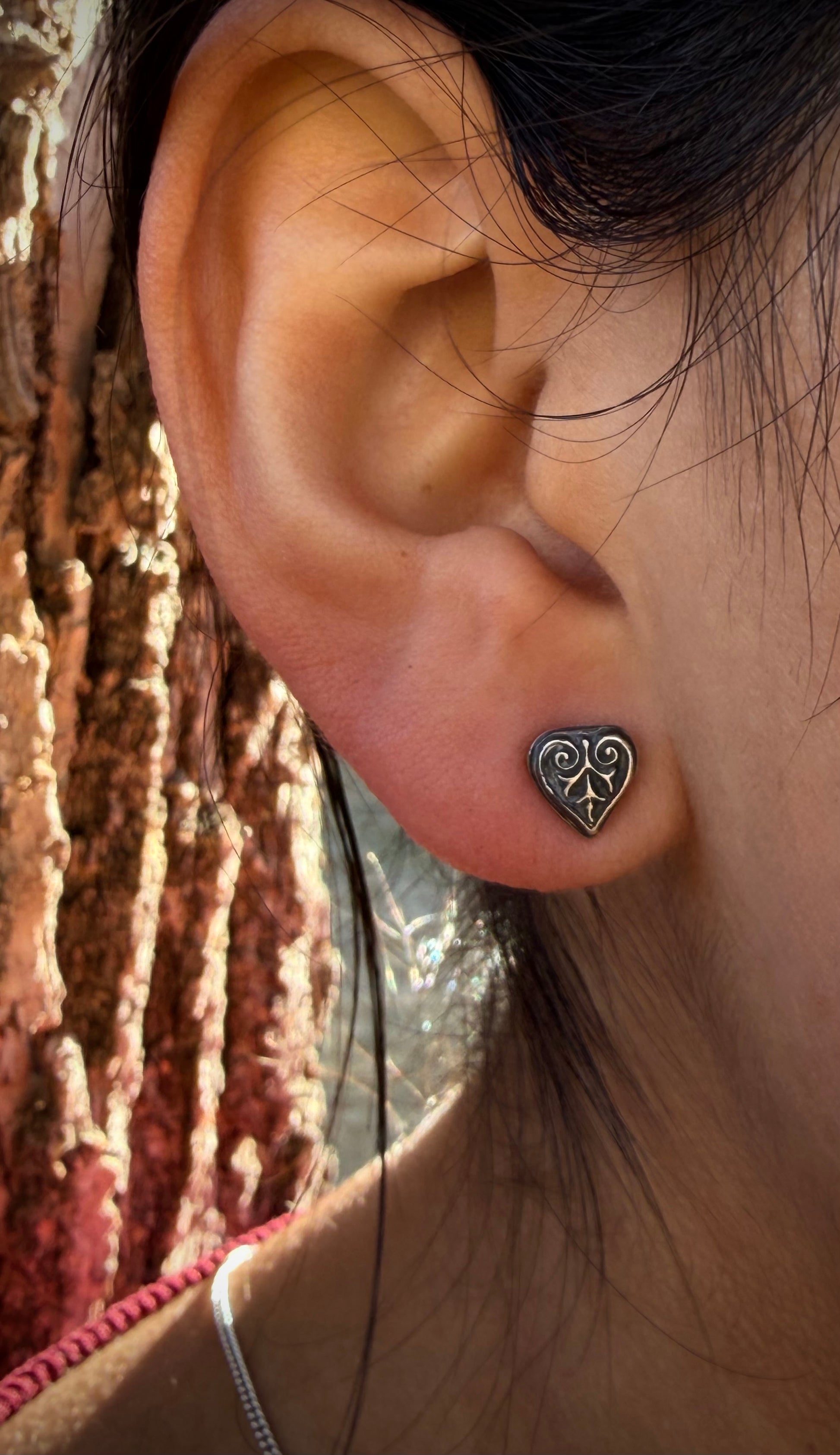 Lifestyle shot of a sterling silver Ashborn stud in a lobe piercing. The polished silver highlights and moody oxidized details complement a minimalist, Dark Academia look.
