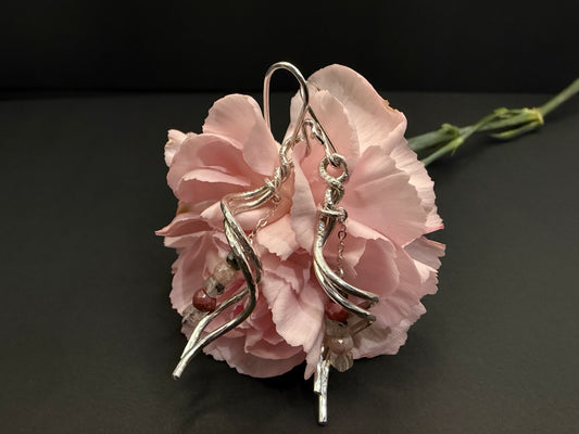 Hand-textured silver Blushthorn earrings with Peach Moonstone and Prehnite gemstone drops, displayed against a soft pink carnation.