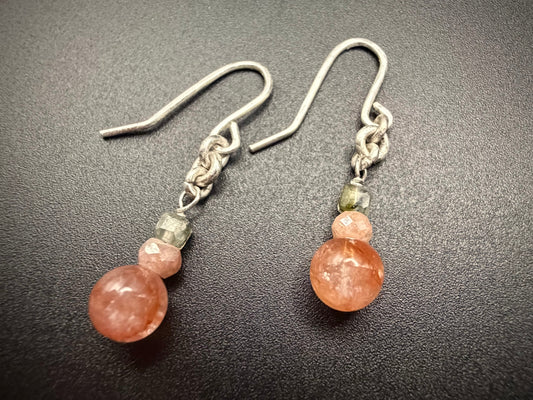 Close-up of Dahlia Drops earrings on a dark surface, featuring stacked Red Agate, Peach Moonstone, and Prehnite beads with sterling silver hooks.