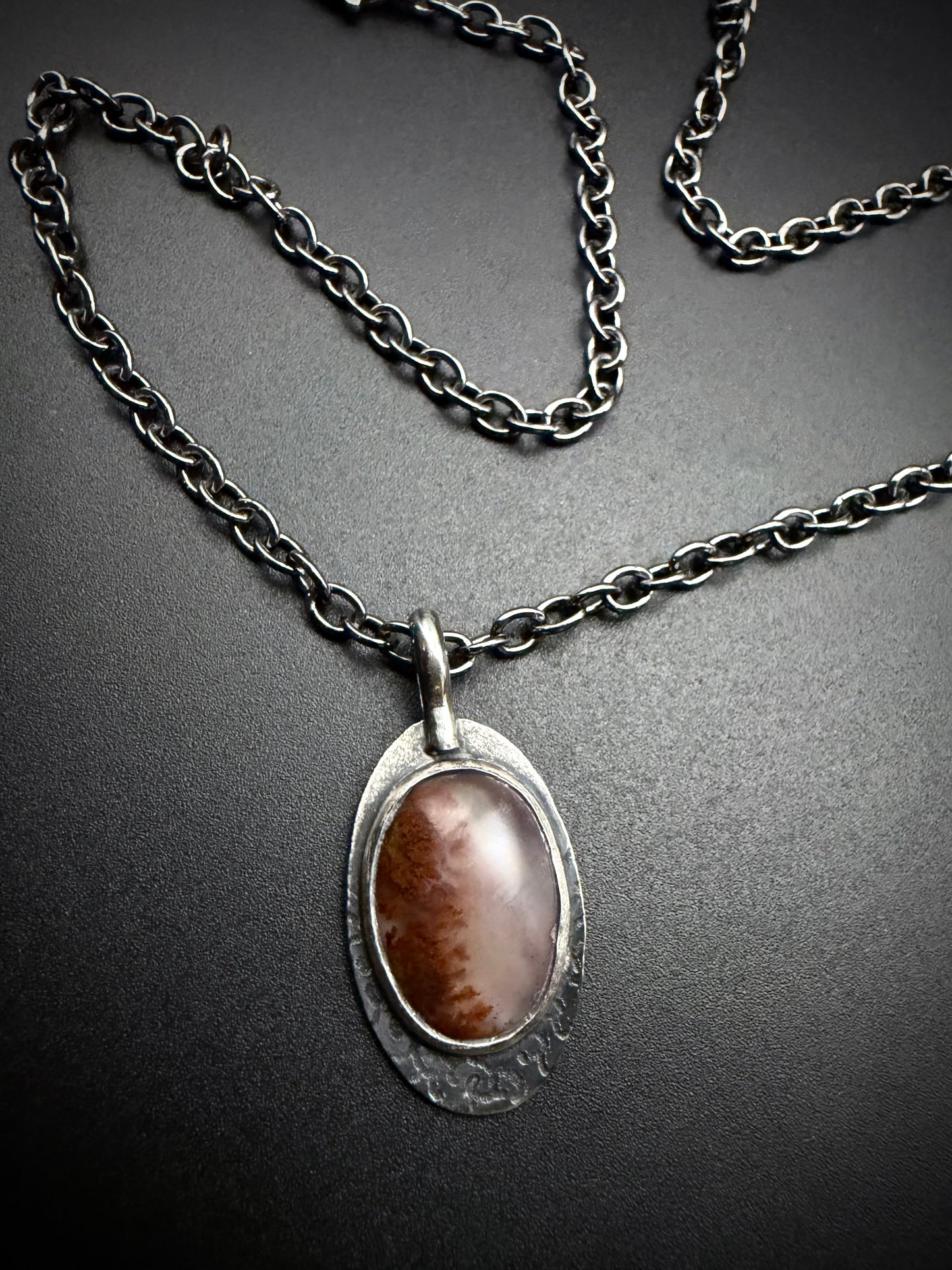 Oval red Plume Agate pendant set in a darkened, textured sterling silver frame on a matching oxidized link chain.