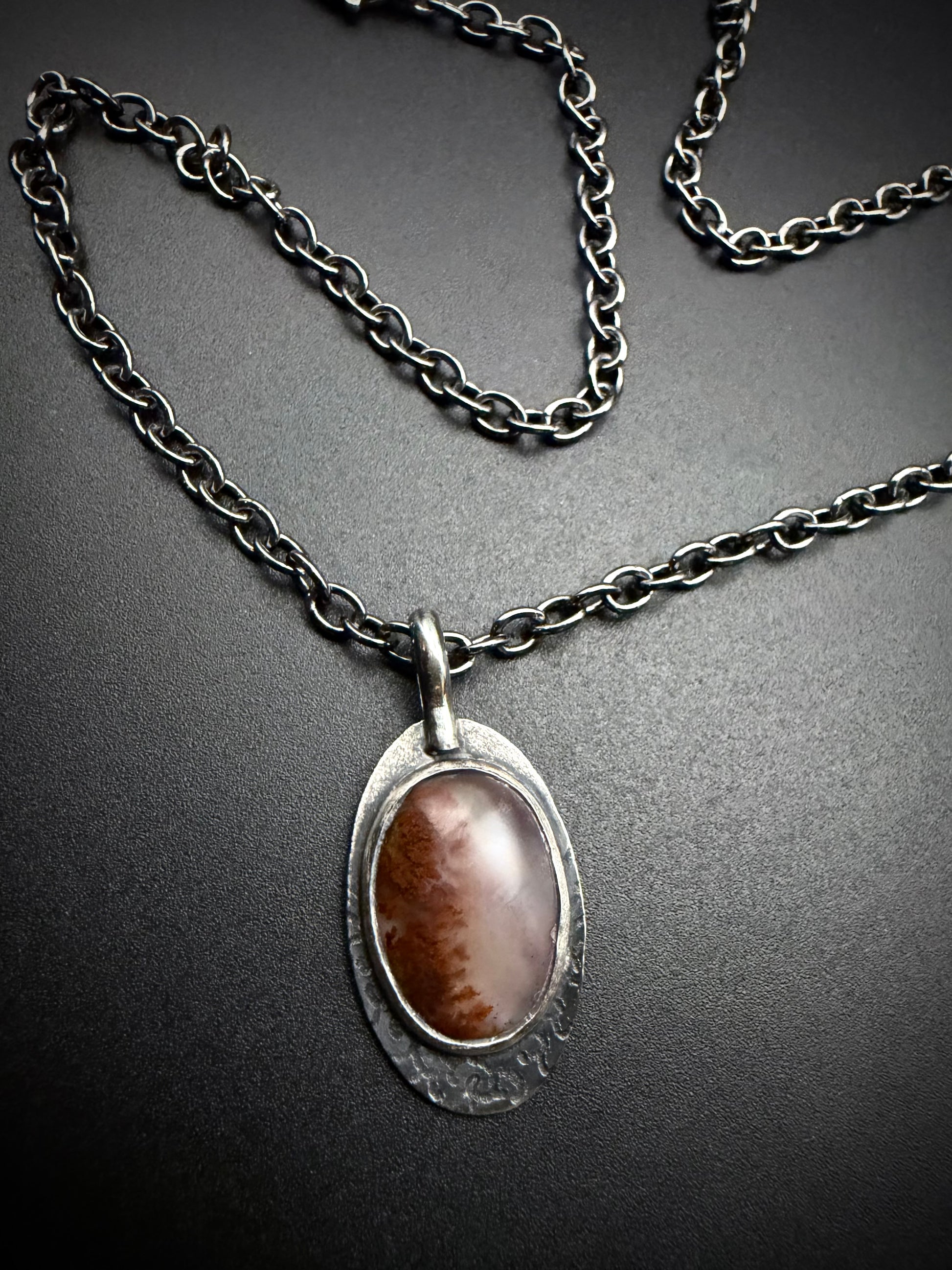 Oval red Plume Agate pendant set in a darkened, textured sterling silver frame on a matching oxidized link chain.