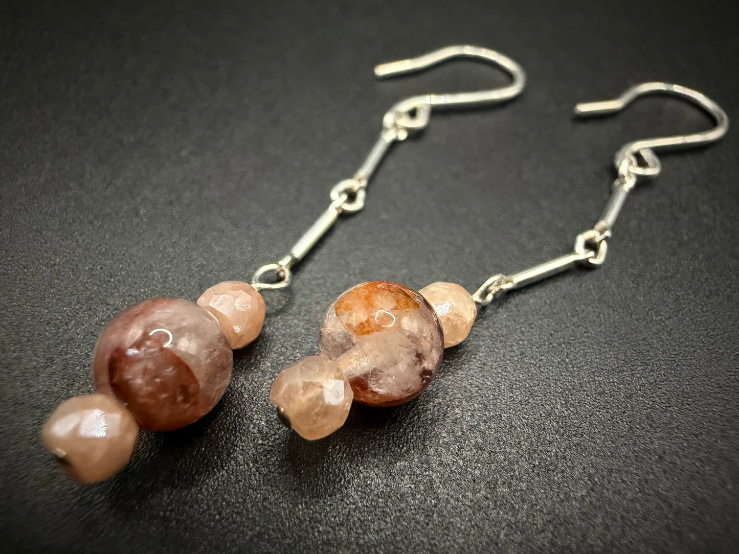 Handcrafted sterling silver drop earrings featuring a tiered arrangement of polished red agate and faceted peach moonstone beads on a silver chain.
