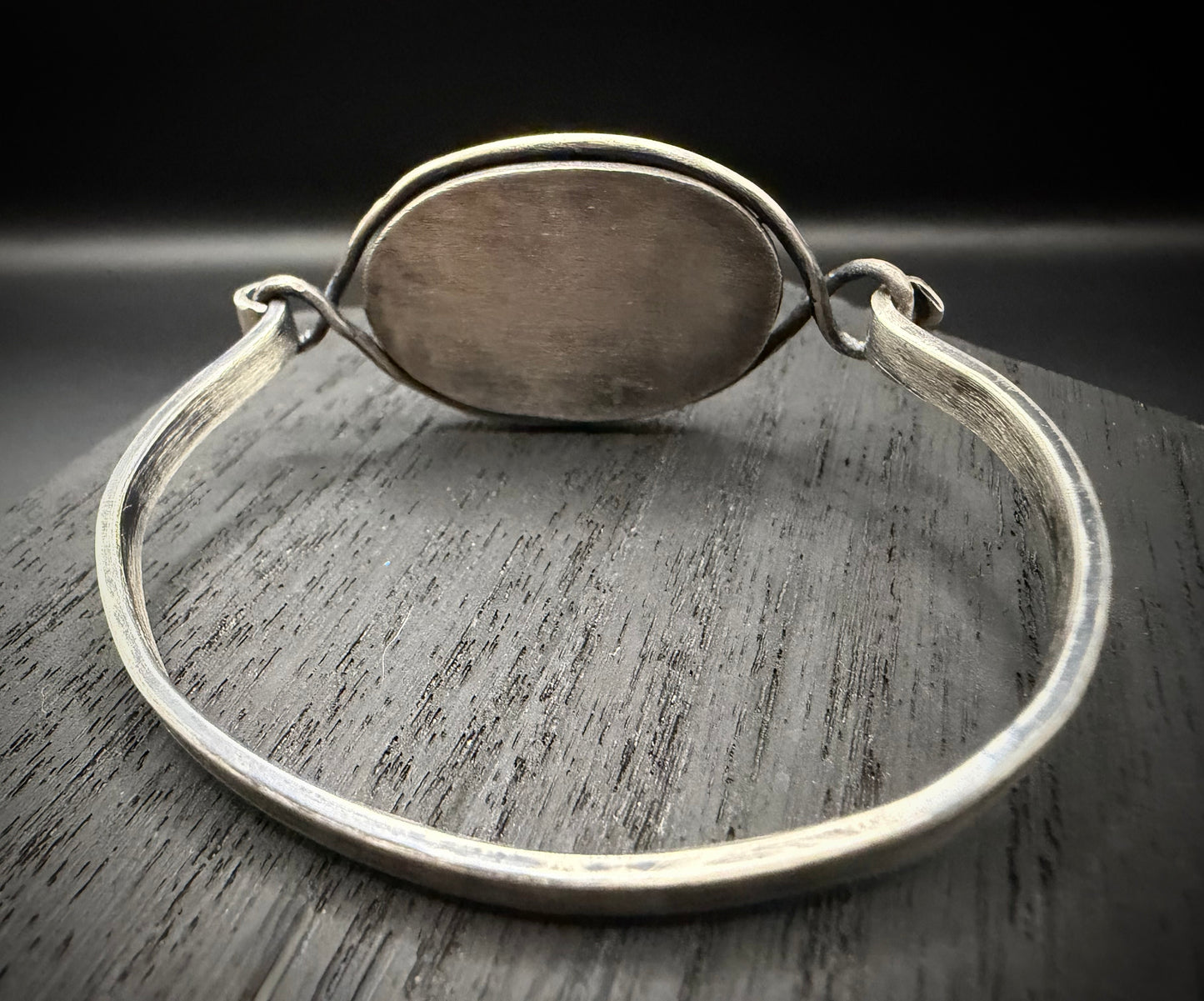 The back view of the handcrafted sterling silver Rootvaern Cuff, showing the secure bezel setting and the intentional weathered texture on the inner band.