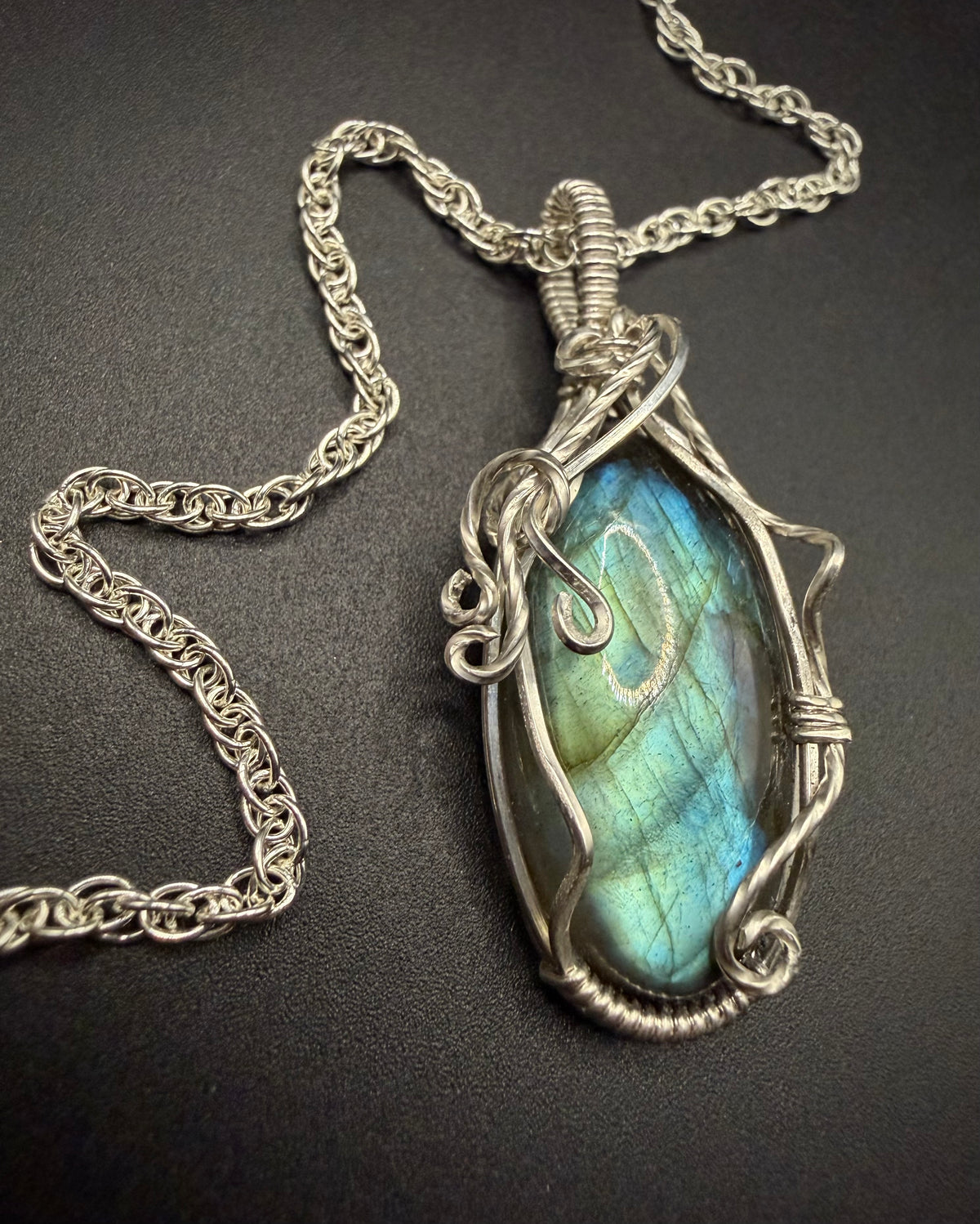Close-up of the Calypso Pendant showing the blue-green flash of the labradorite stone and intricate silver vine wirework.