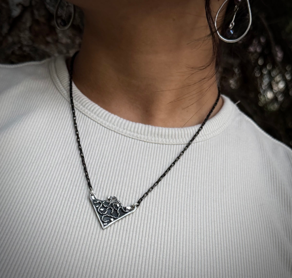 Close up view of the silver Thoth Pendant resting at the collarbone, highlighting its openwork geometric design and dark patina.