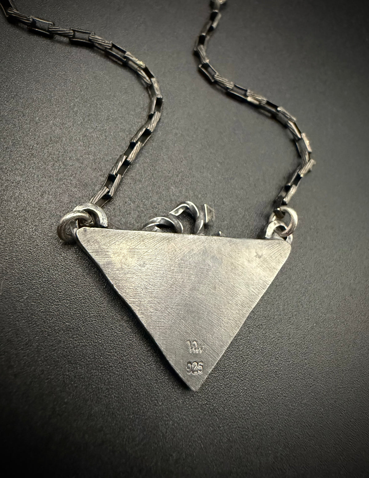 Close up view of the reverse side of the triangular Thoth Pendant featuring a textured backplate and double jump ring attachments.