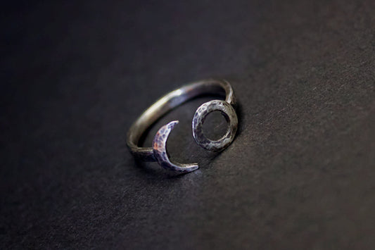 Silver ring with moon and circle design on a dark surface
