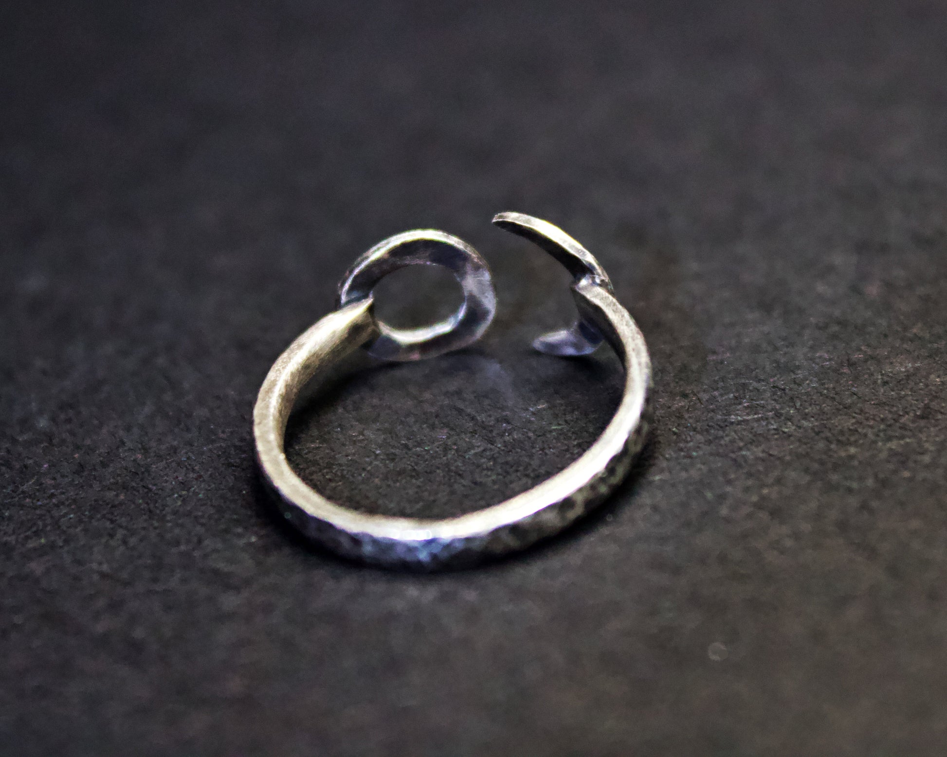 Silver ring with a unique design on a dark background