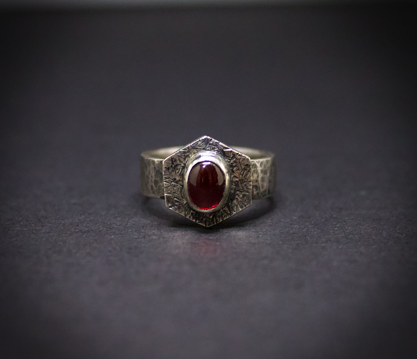 Silver ring with a red gemstone on a dark gray background