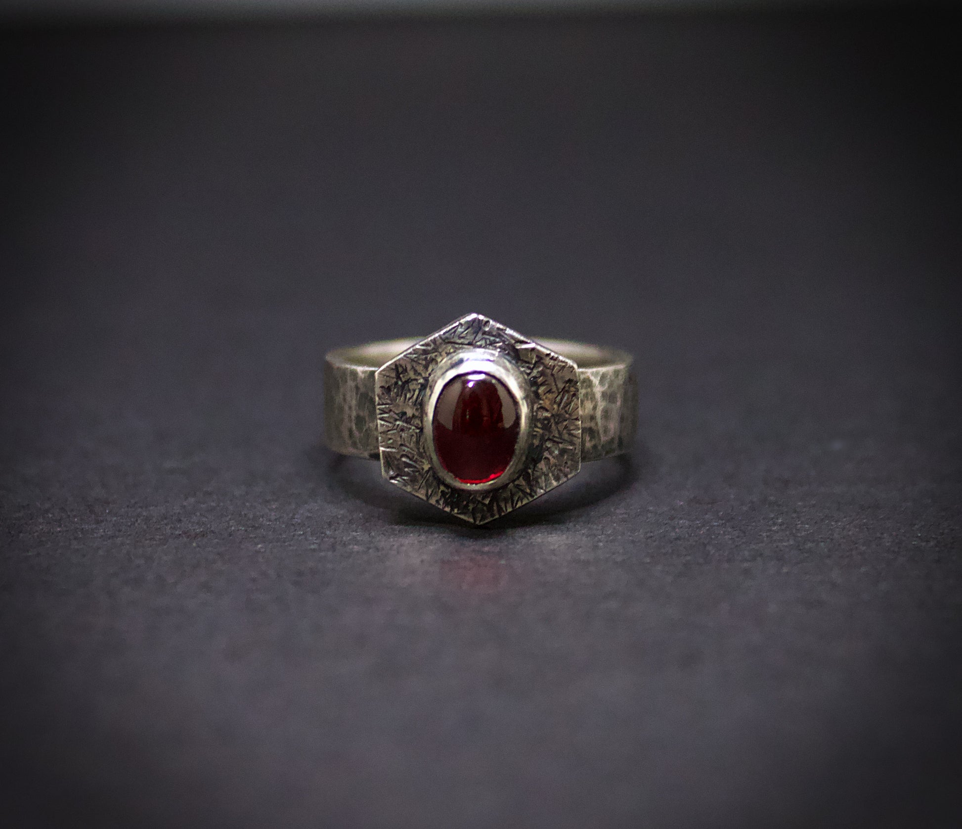 Silver ring with a red gemstone on a dark gray background