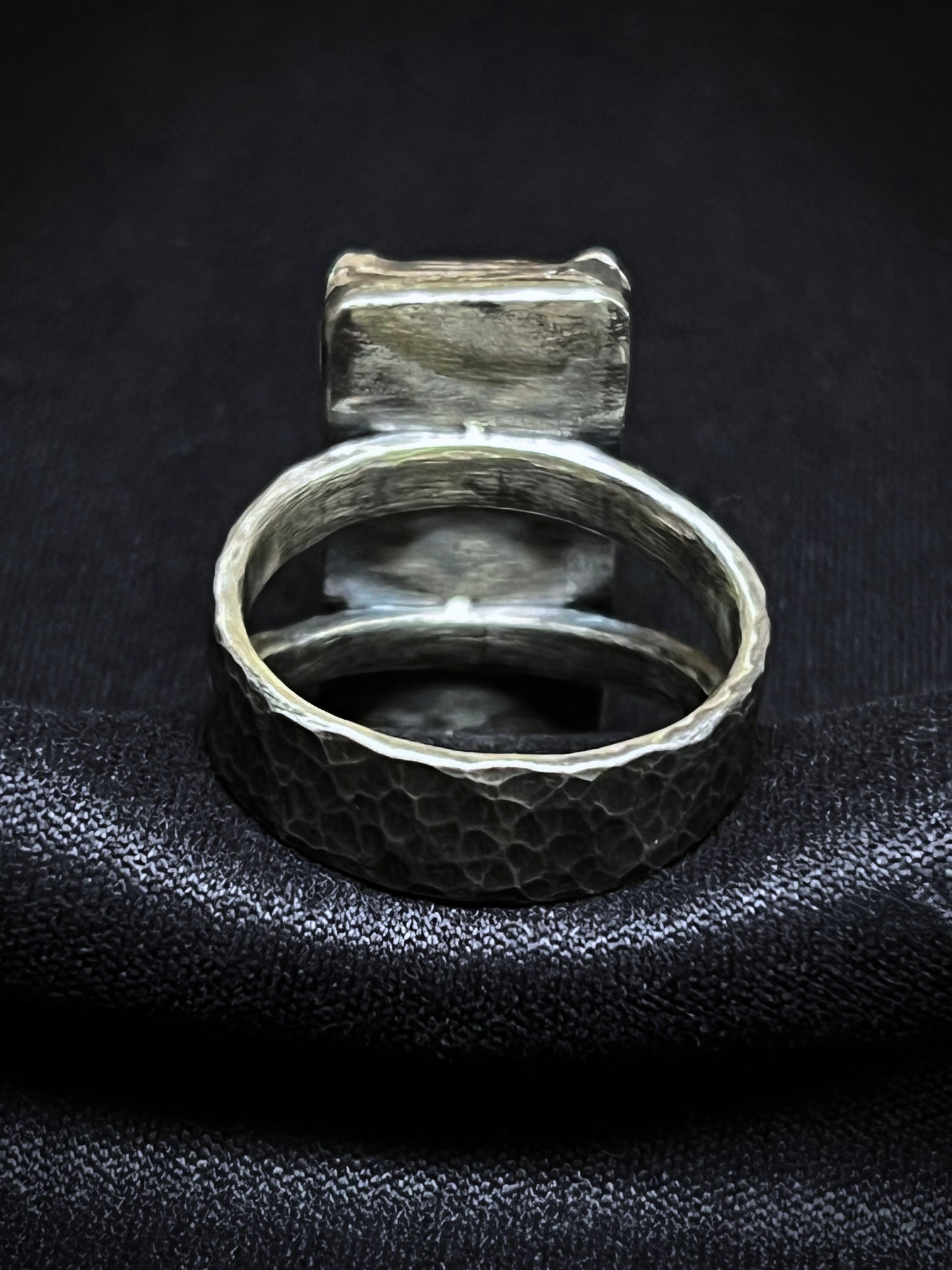 Silver ring with textured band on a black textured surface