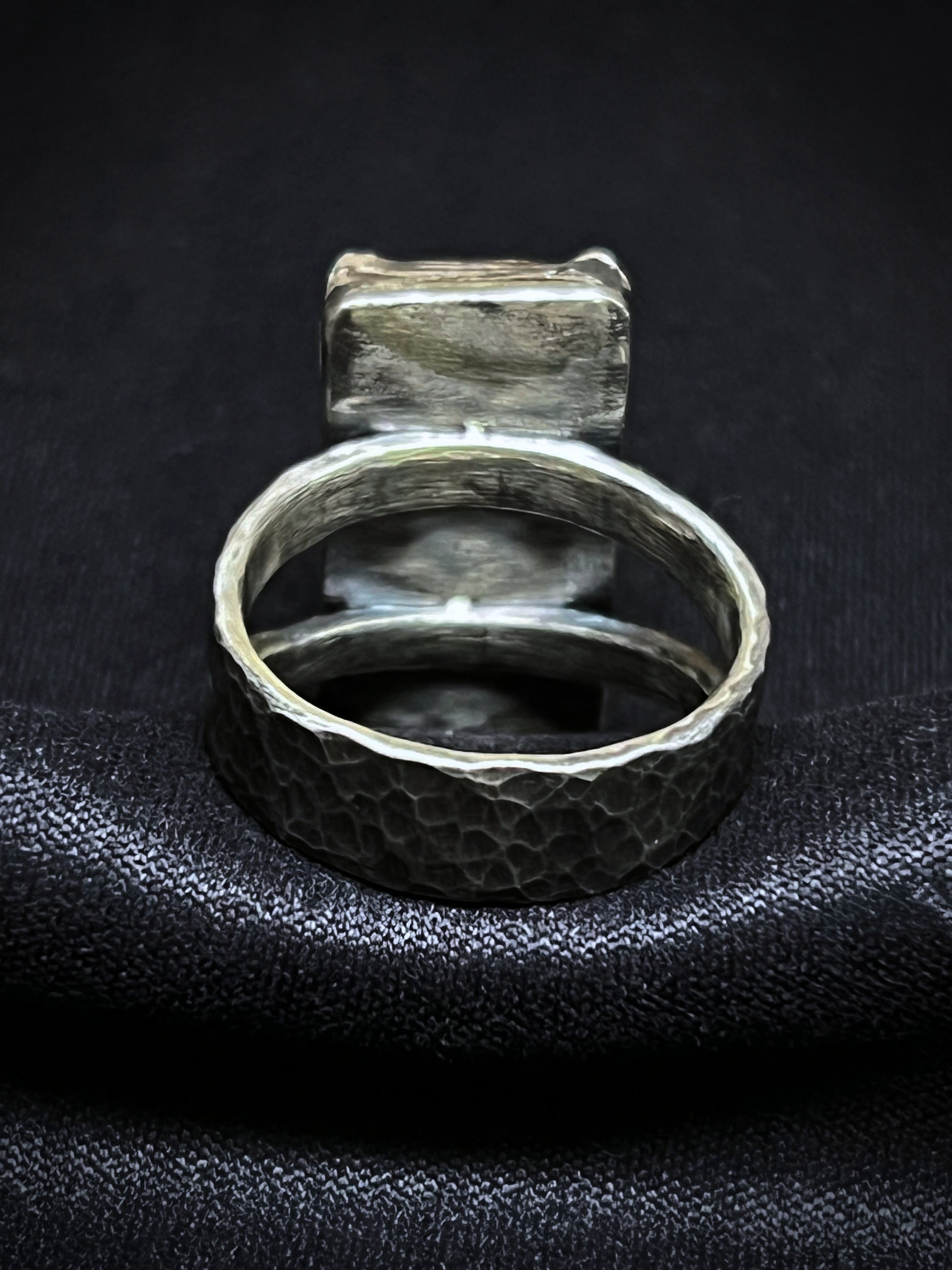 Silver ring with textured band on a black textured surface