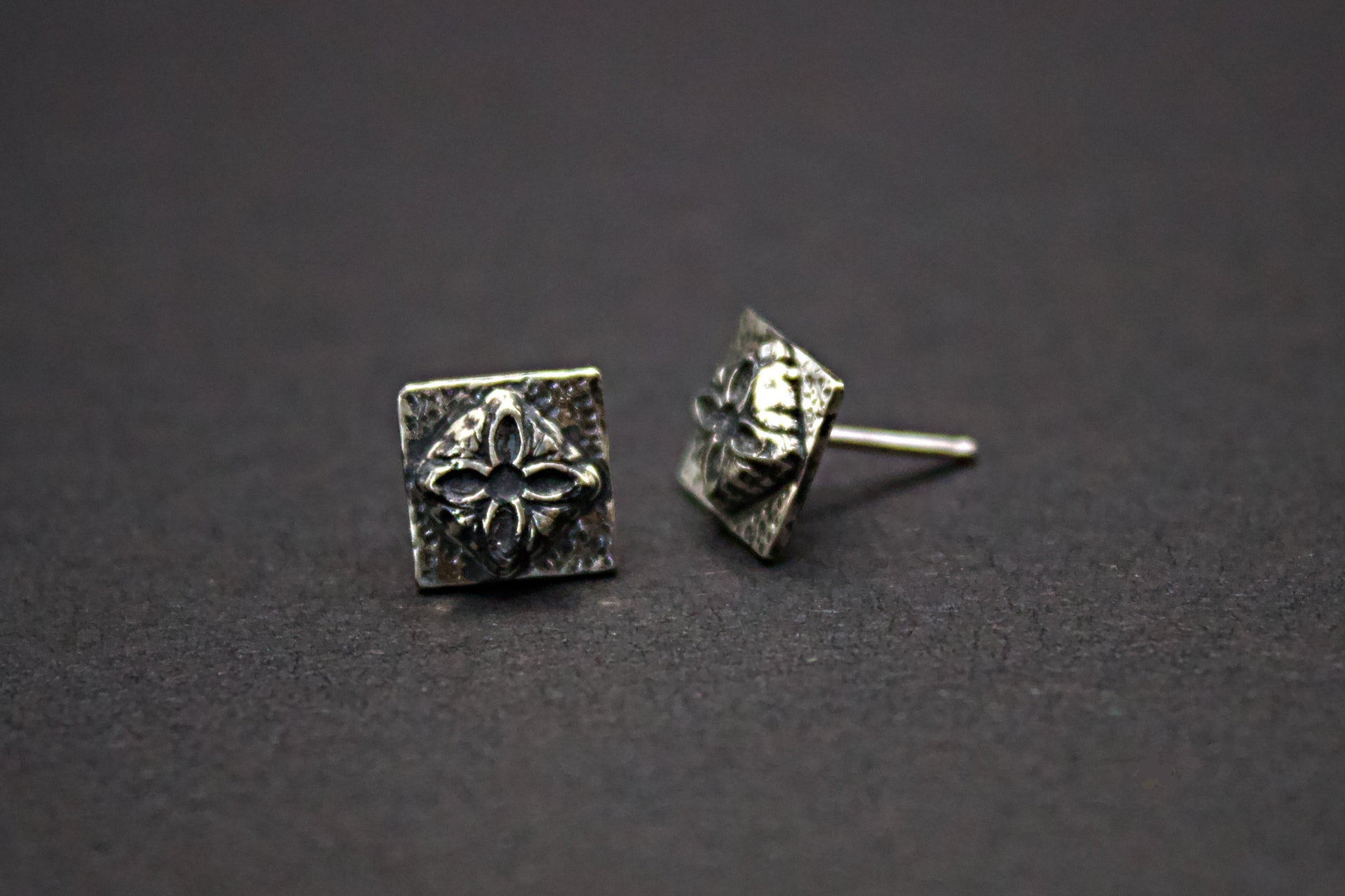 Pair of silver square earrings on a dark background
