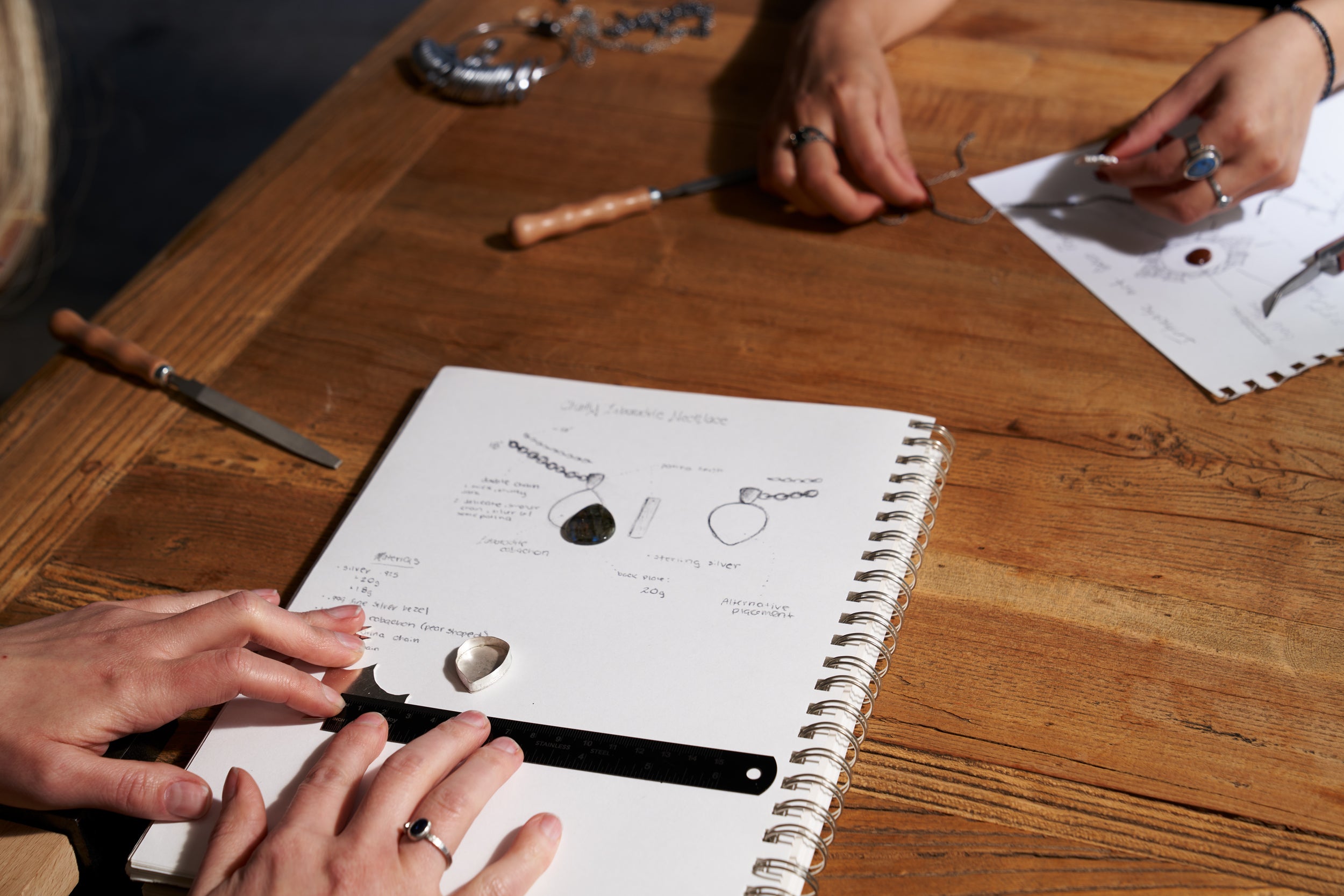 People working on a project with tools and a notebook on a wooden table