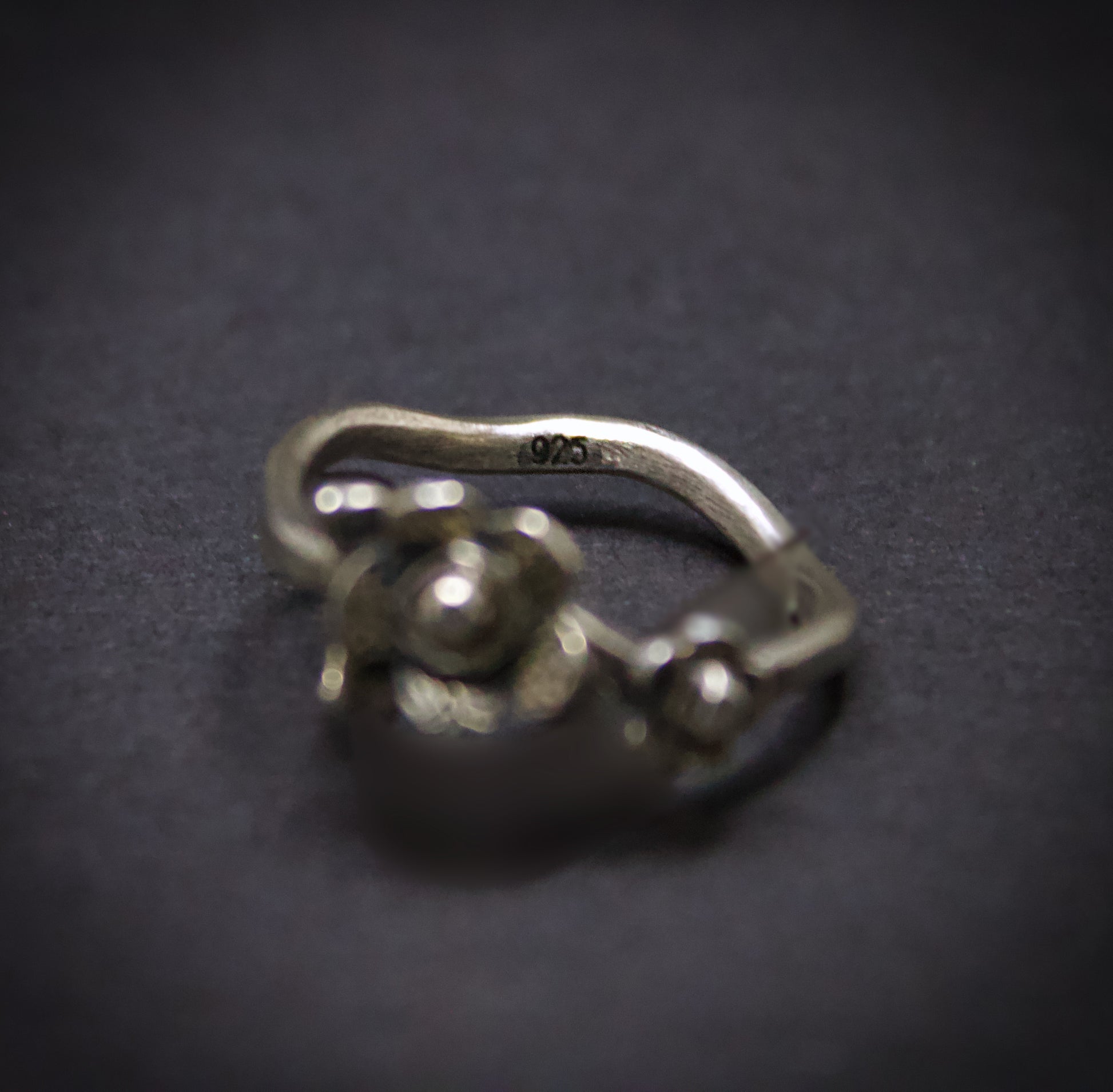 Silver ring with floral design on a dark background