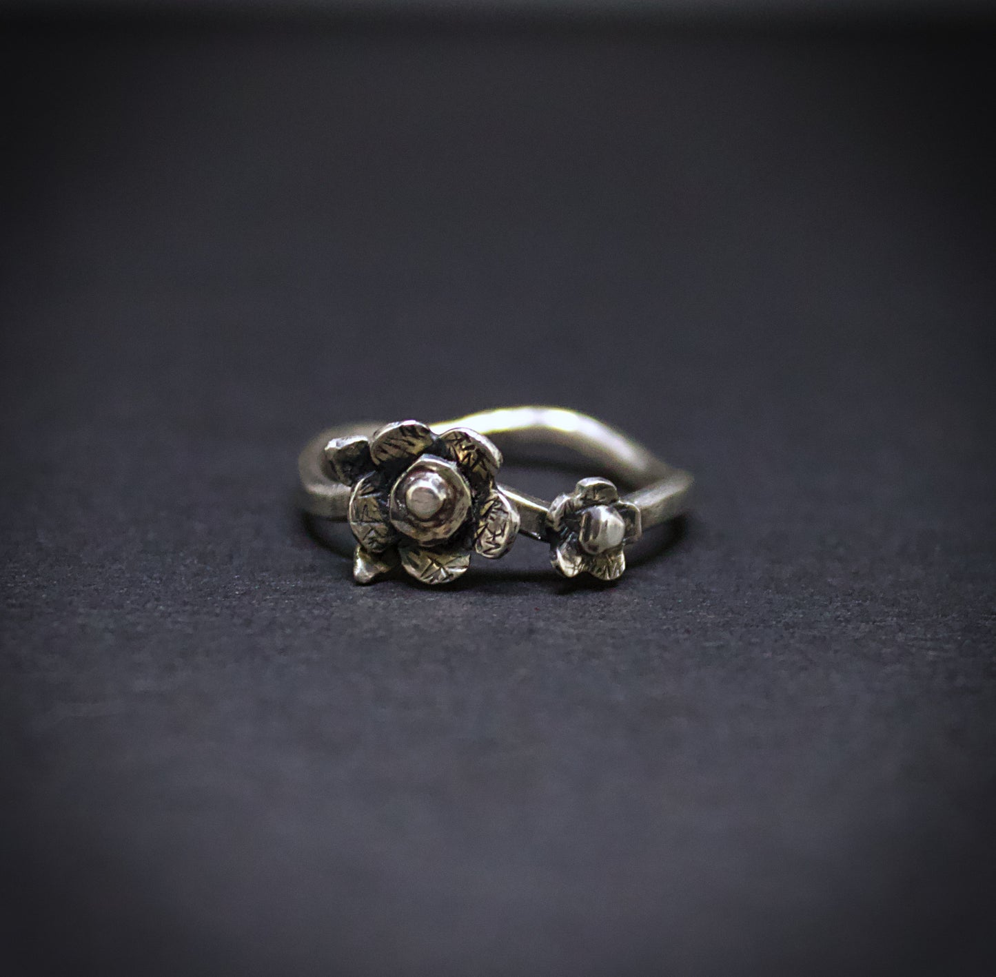 Silver floral ring on a dark background