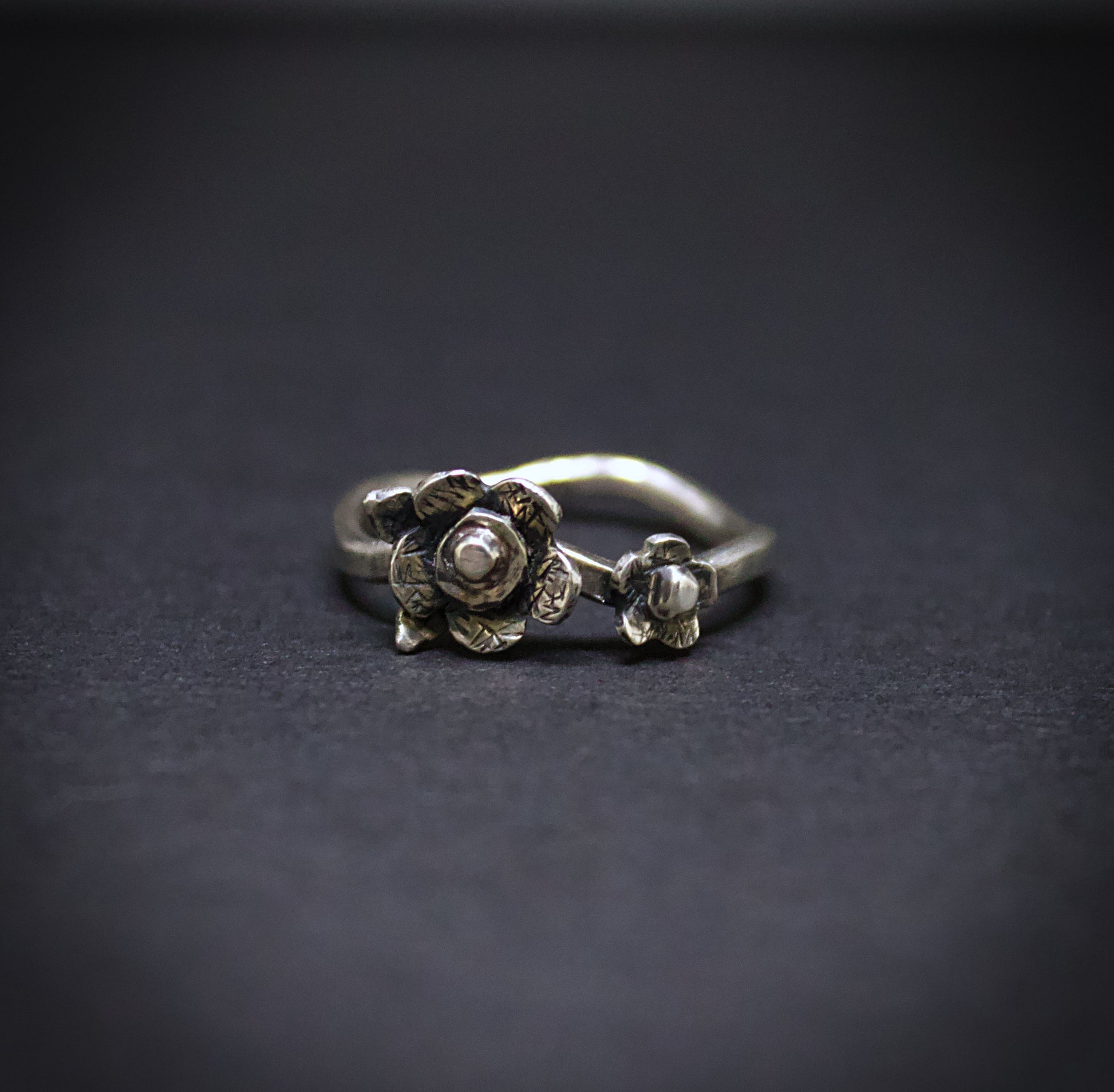 Silver floral ring on a dark background