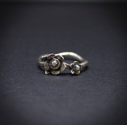 Silver floral ring on a dark background